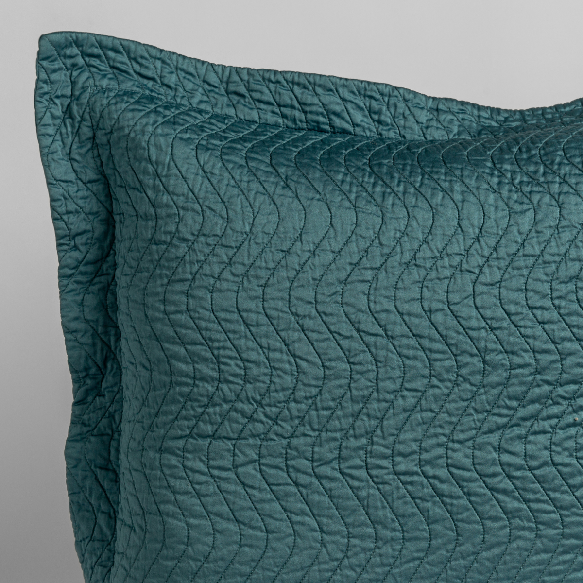 Cenote: close up of the corner of a quilted cotton sateen pillow sham - shot against a white background.
