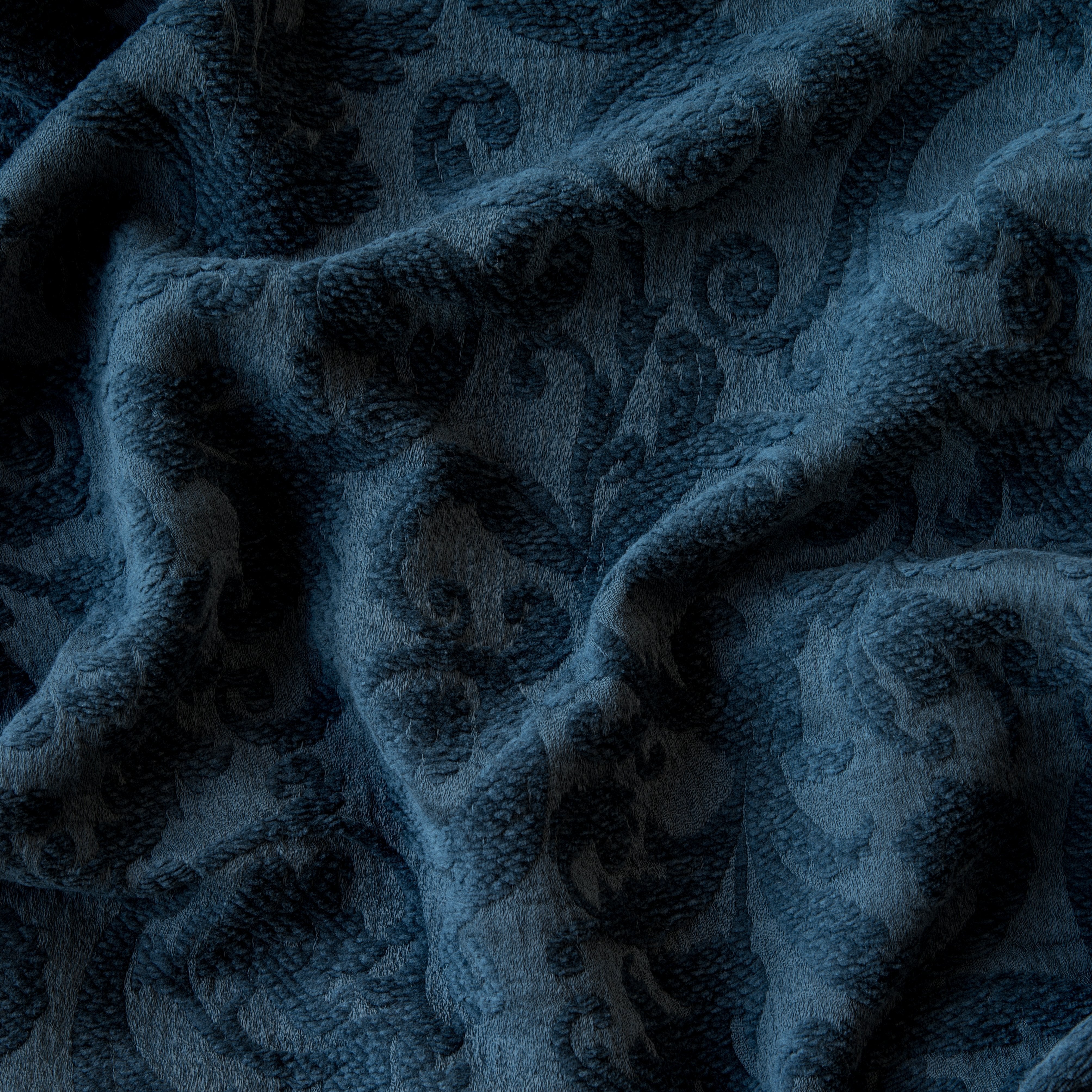 Midnight: A close up of Adele fabric in midnight, a rich indigo tone. The fabric is rumpled to show the cotton damask texture.