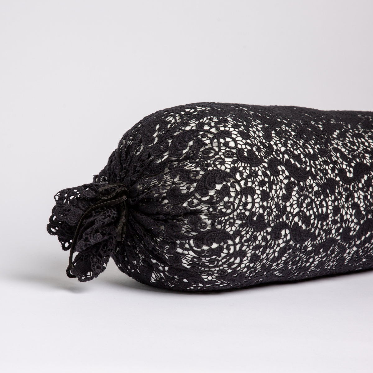 Corvino: one end of a lace boslter cover on a winter white liner against a white background.