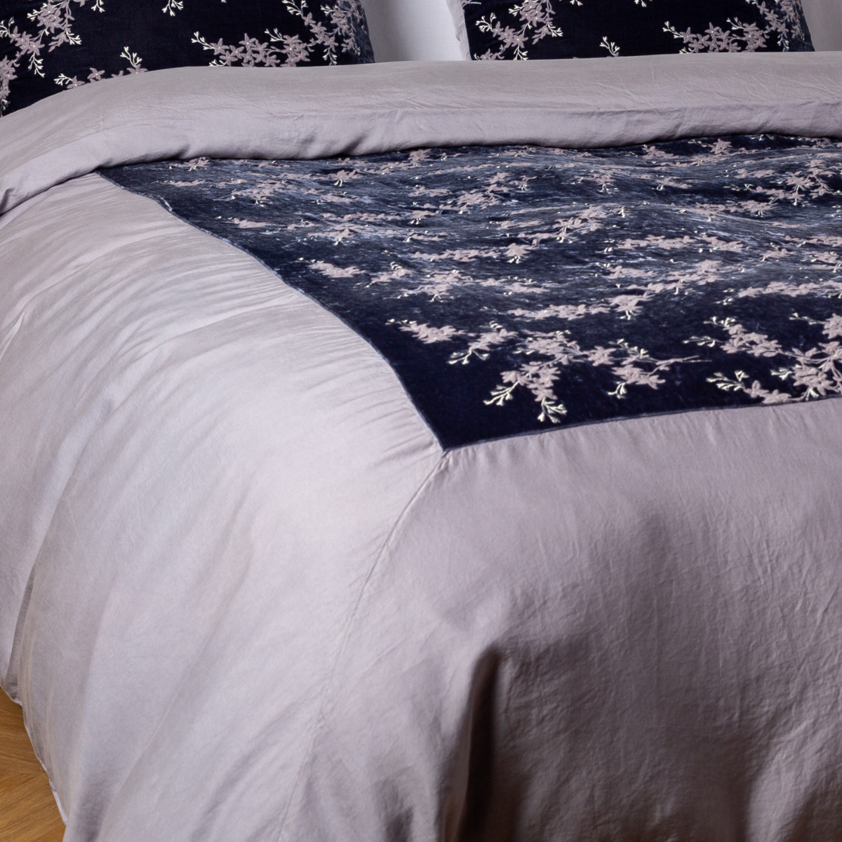 French Lavender: A close-up of the mitered corner of an embroidered silk velvet and tencel duvet cover — its matching shams barely visible in the shot.