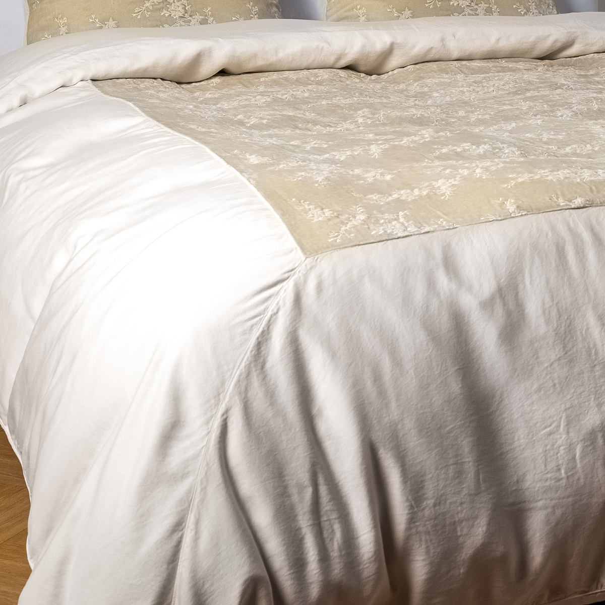 Parchment: A close-up of the mitered corner of an embroidered silk velvet and tencel duvet cover — its matching shams barely visible in the shot.