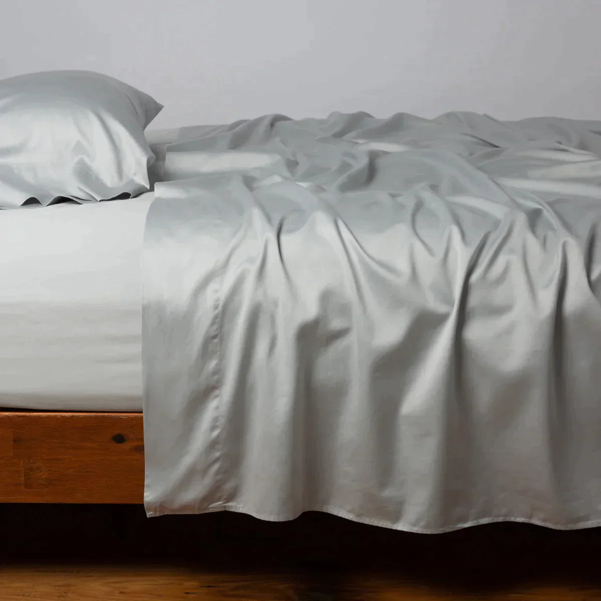 Cloud: Cotton sateen flat sheet, shown with matching fitted sheet and sleeping pillow - side view.