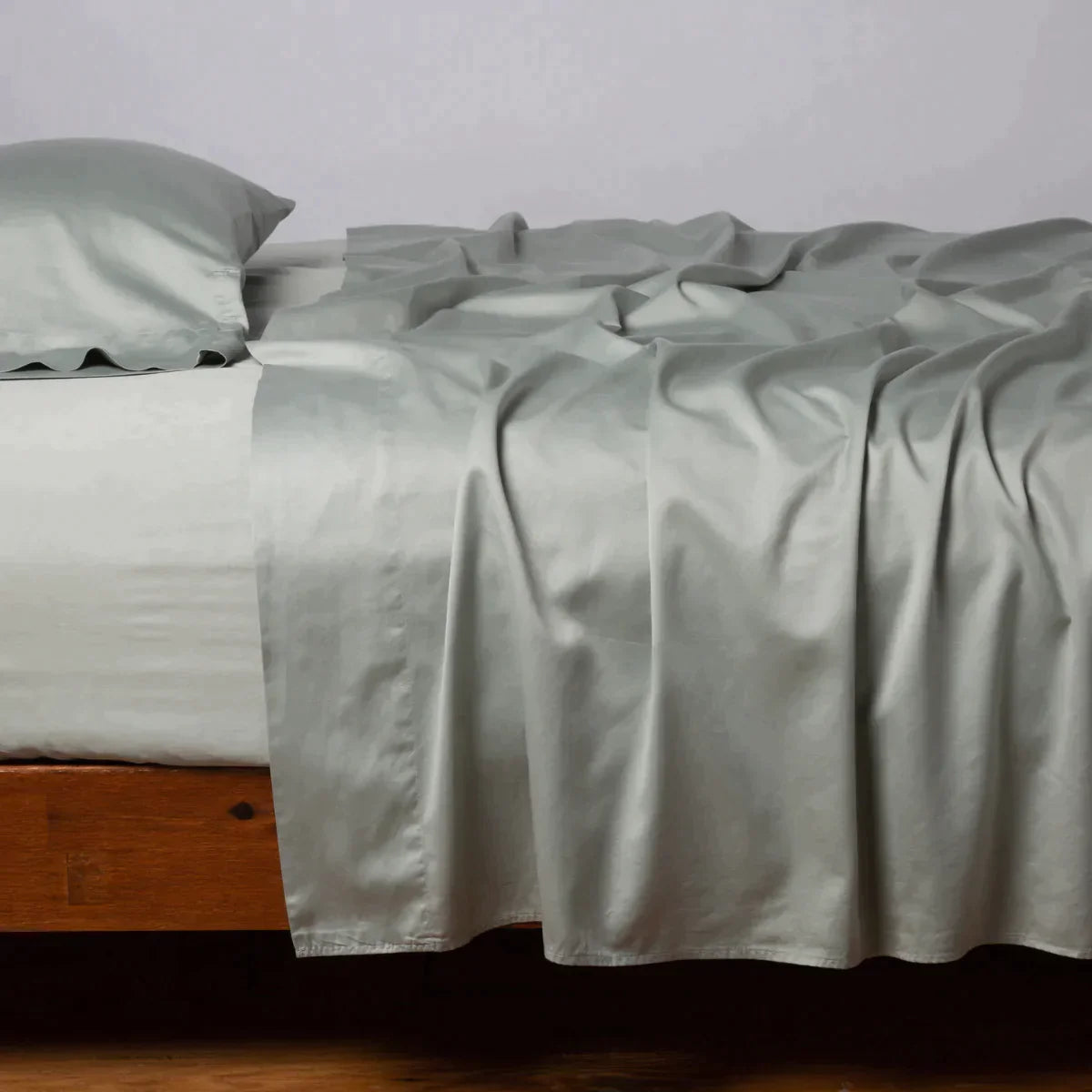 Eucalyptus: Cotton sateen flat sheet, shown with matching fitted sheet and sleeping pillow - side view.