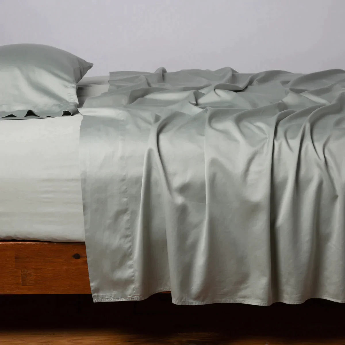 Eucalyptus: Cotton sateen flat sheet, shown with matching fitted sheet and sleeping pillow - side view.