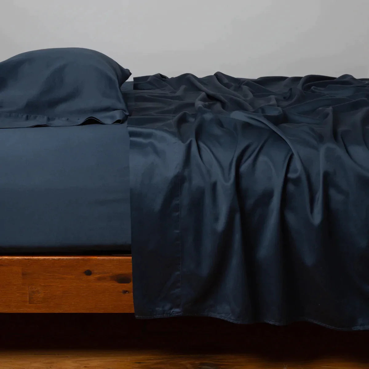 Midnight: Cotton sateen flat sheet, shown with matching fitted sheet and sleeping pillow - side view.