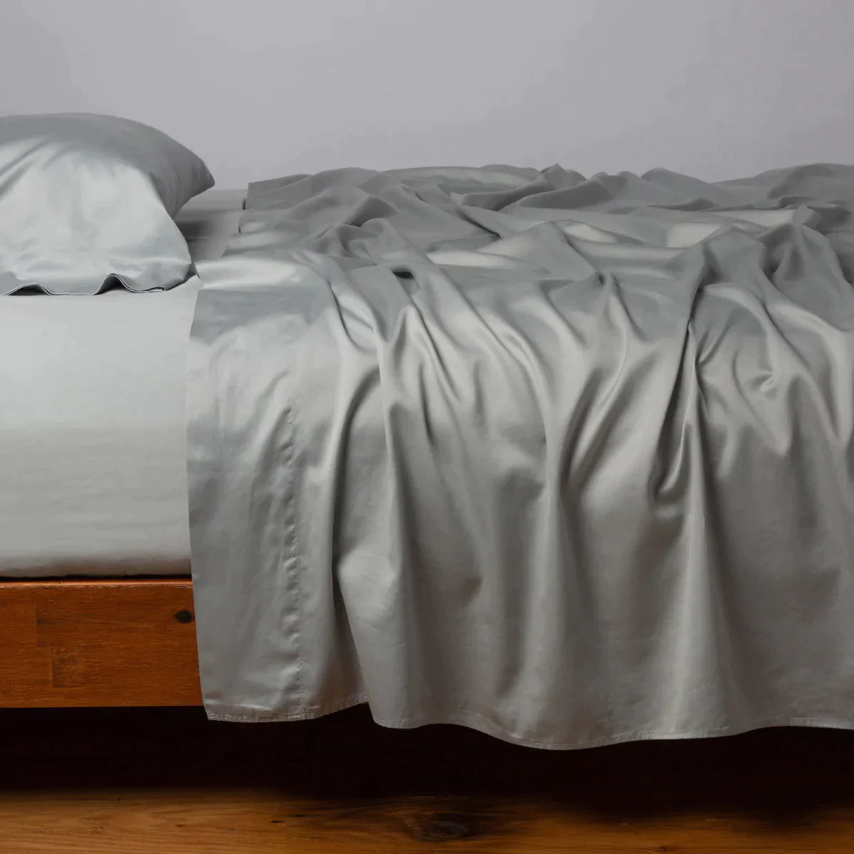 Mineral: Cotton sateen flat sheet, shown with matching fitted sheet and sleeping pillow - side view.