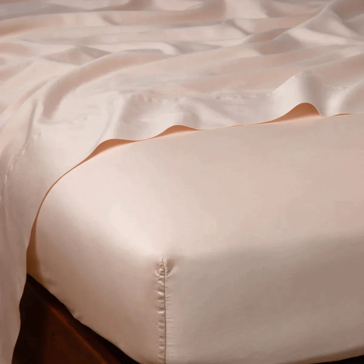 Pearl: Cotton sateen flat sheet draped over matching fitted sheet. Shown from the top corner, the flat sheet is rumpled, highlighting the shine of the fabric.
