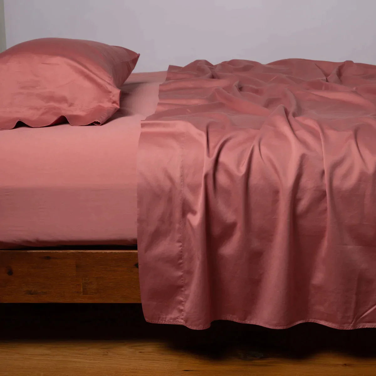 Poppy: Cotton sateen flat sheet, shown with matching fitted sheet and sleeping pillow - side view.