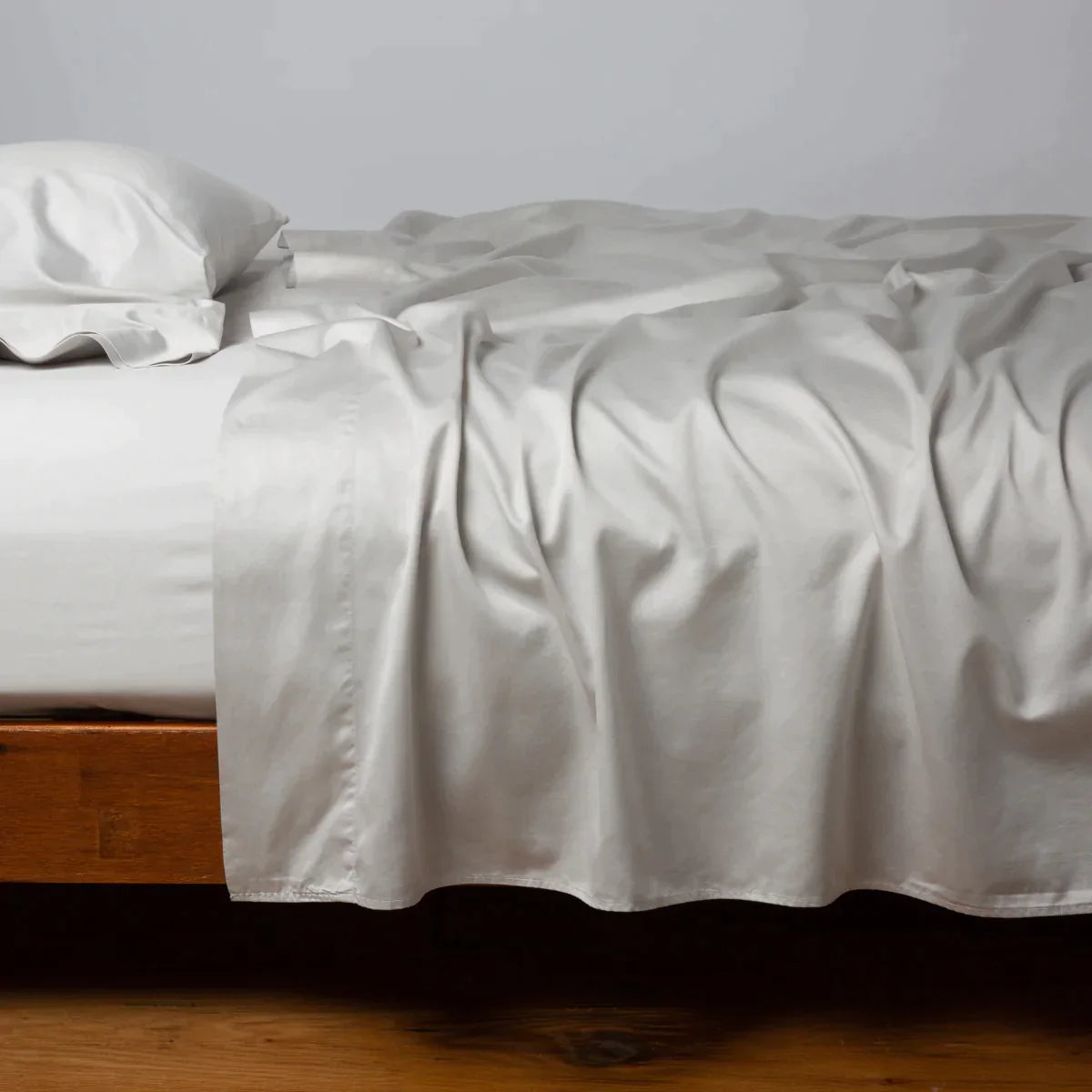 Sterling: Cotton sateen flat sheet, shown with matching fitted sheet and sleeping pillow - side view.