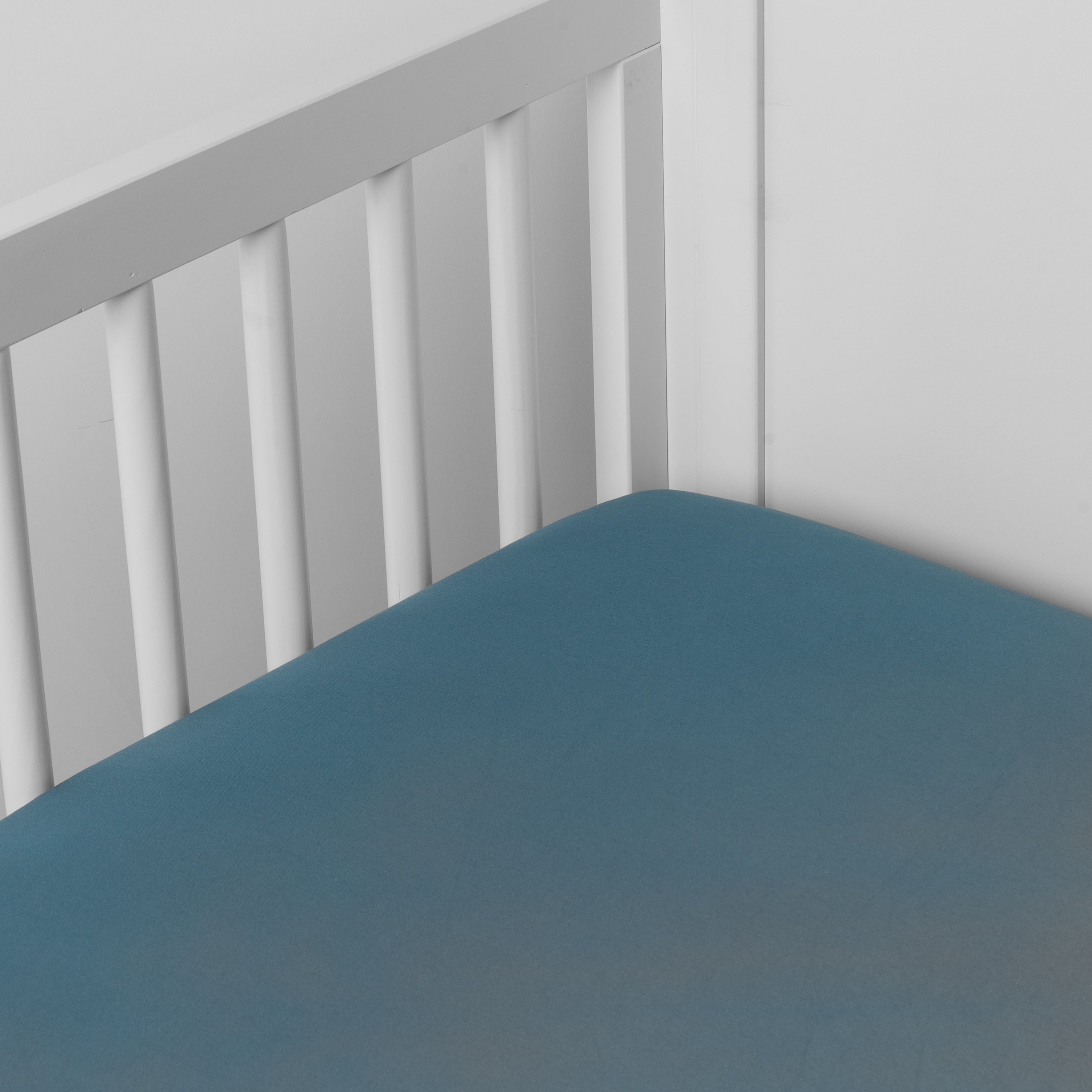 Cenote: Cotton sateen crib sheet shown from a slight overhead angle into an inside corner of a crib.