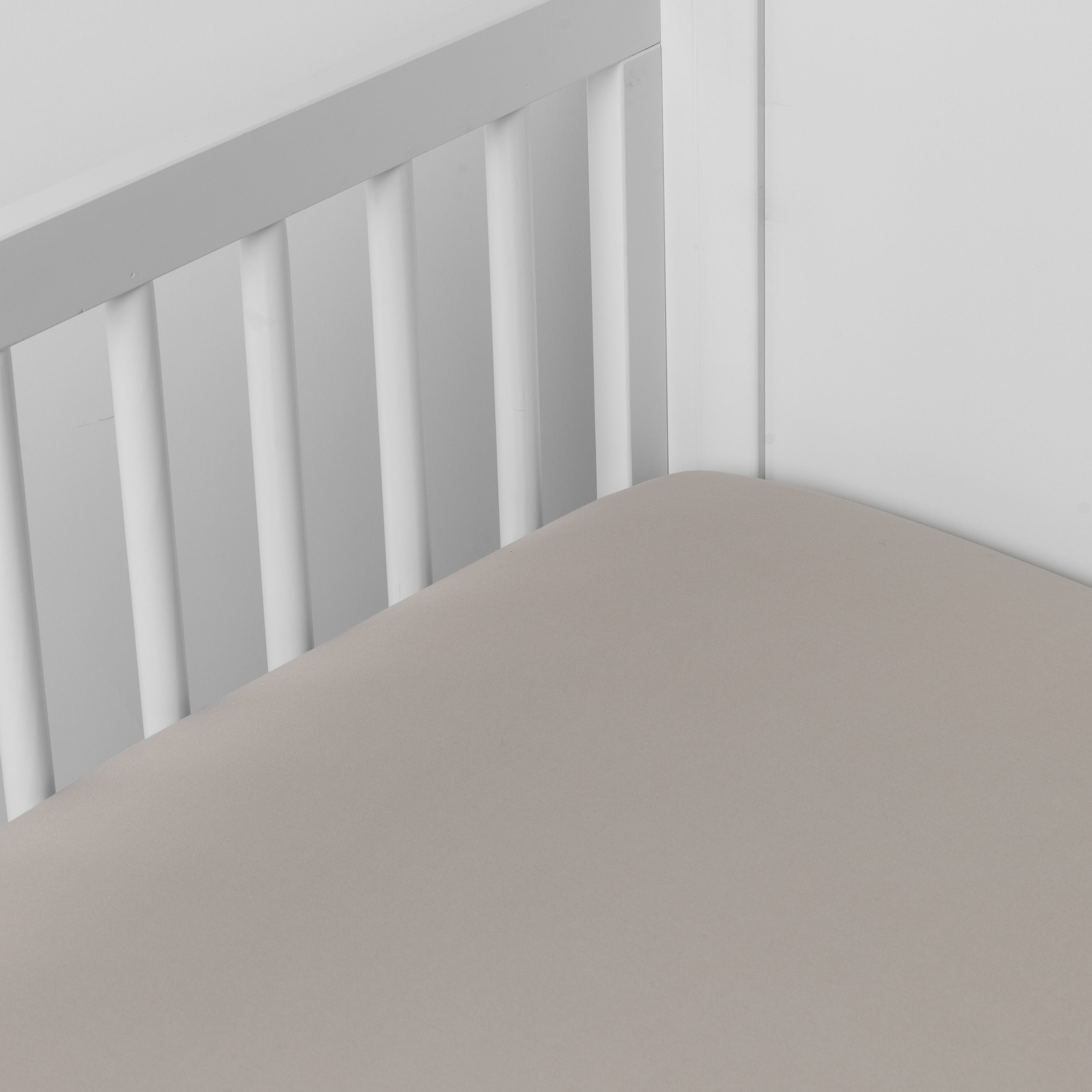 Fog: Cotton sateen crib sheet shown from a slight overhead angle into an inside corner of a crib.