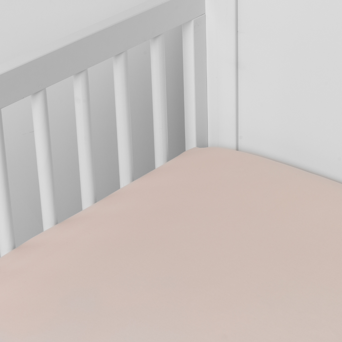 Pearl: Cotton sateen crib sheet shown from a slight overhead angle into an inside corner of a crib.