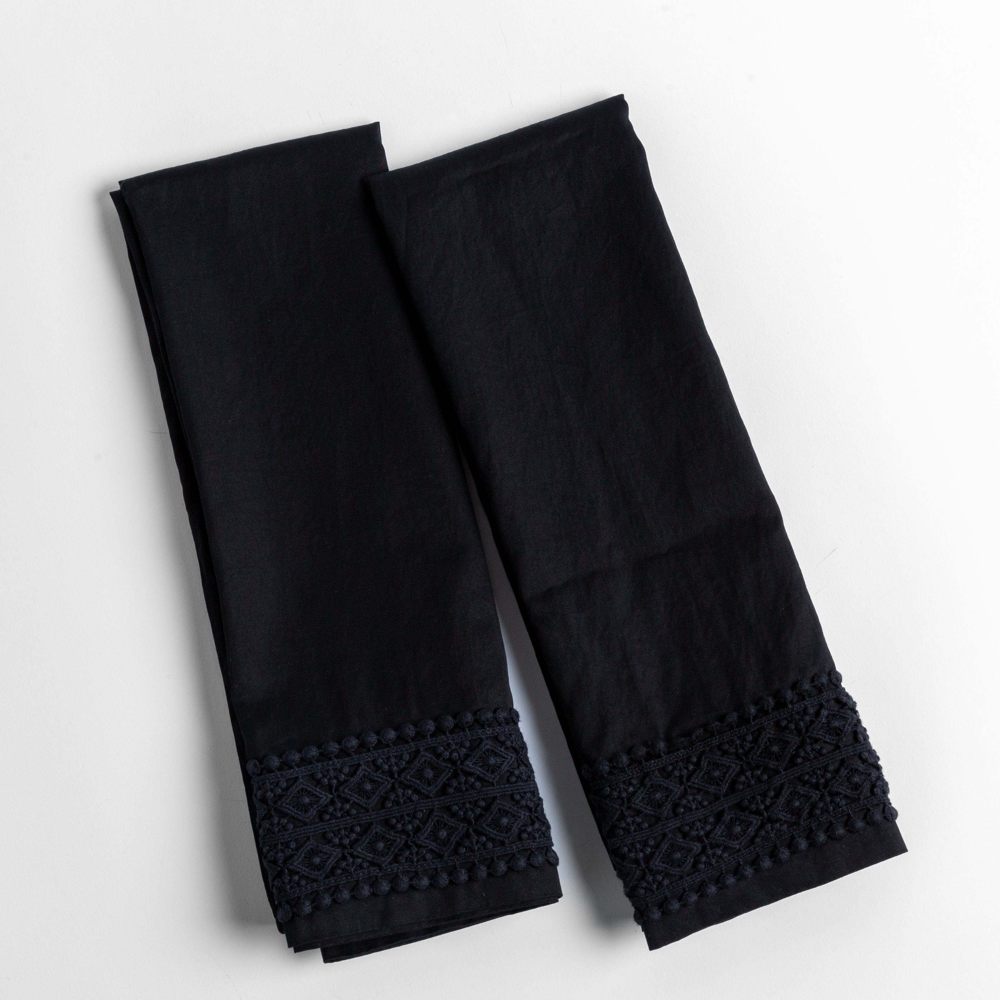 An overhead shot of a folded pair of lace trimmed pillowcases shown side by side and slightly overlapping.