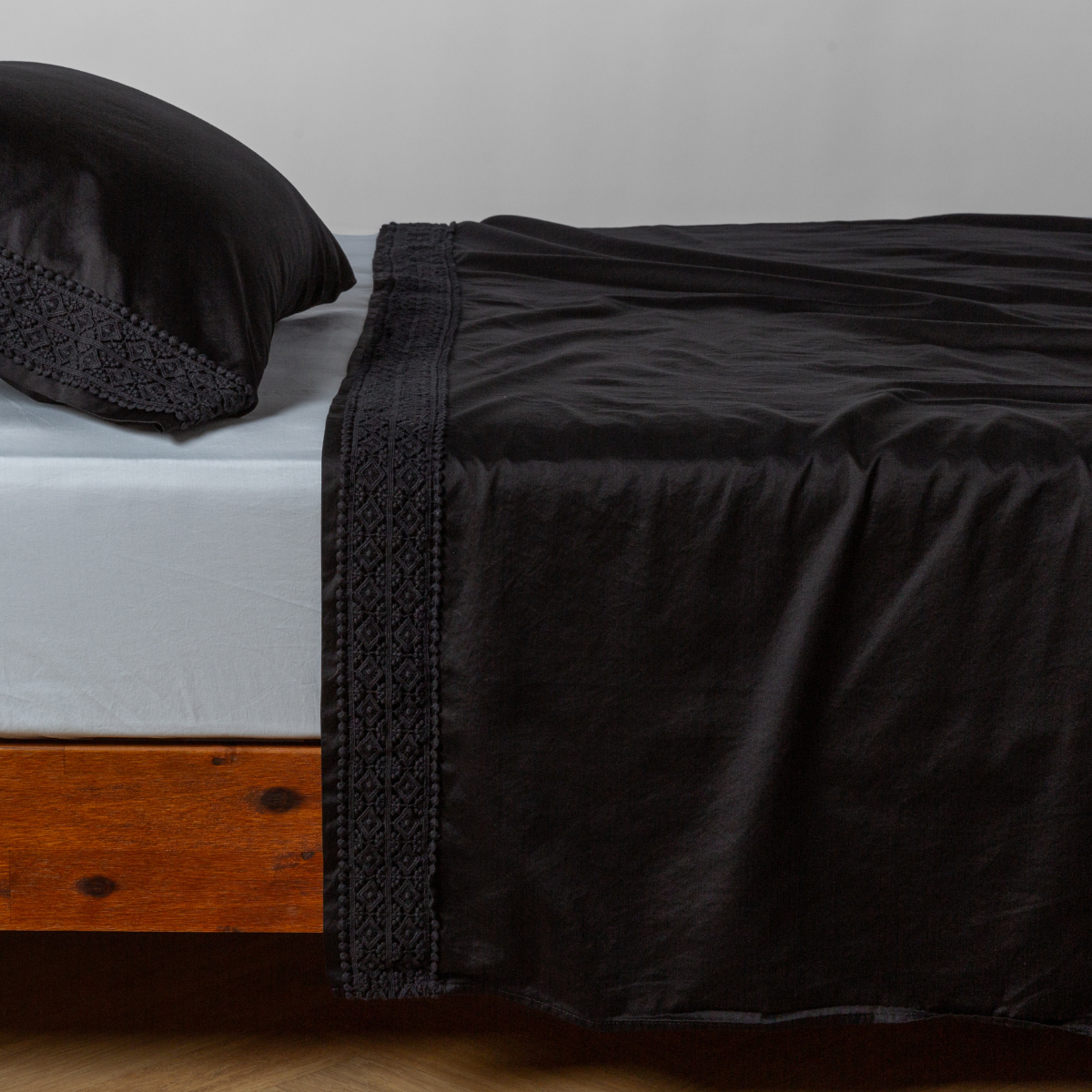 Matching lace trimmed cotton sateen flat sheet and pillowcase shown with a winter white fitted sheet - side view.