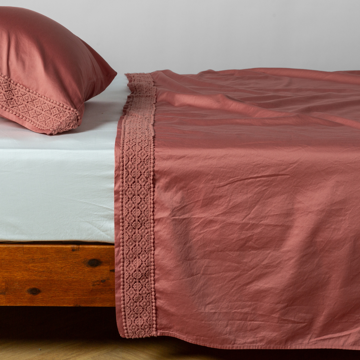 Matching lace trimmed cotton sateen flat sheet and pillowcase shown with a winter white fitted sheet - side view.