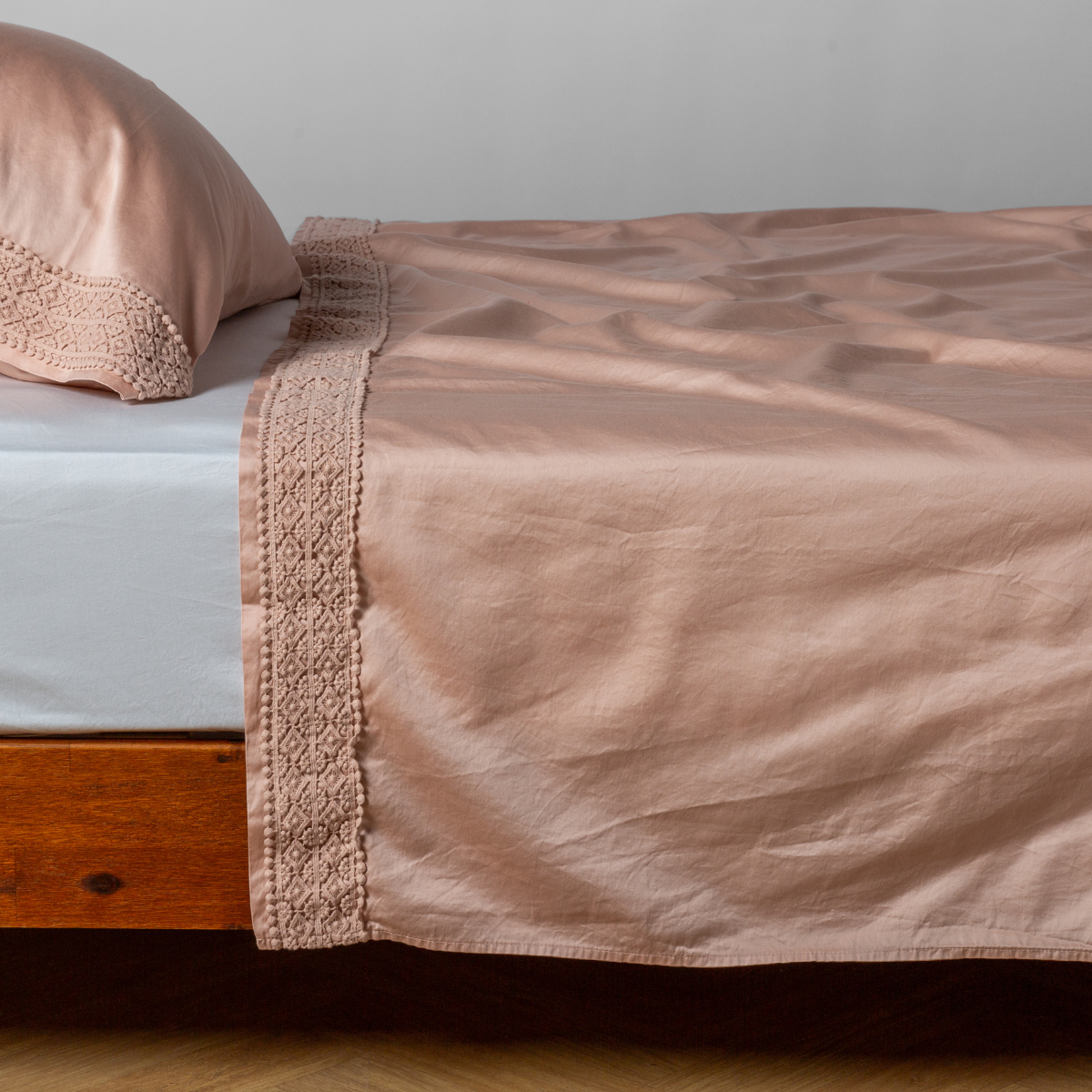 Matching lace trimmed cotton sateen flat sheet and pillowcase shown with a winter white fitted sheet - side view.