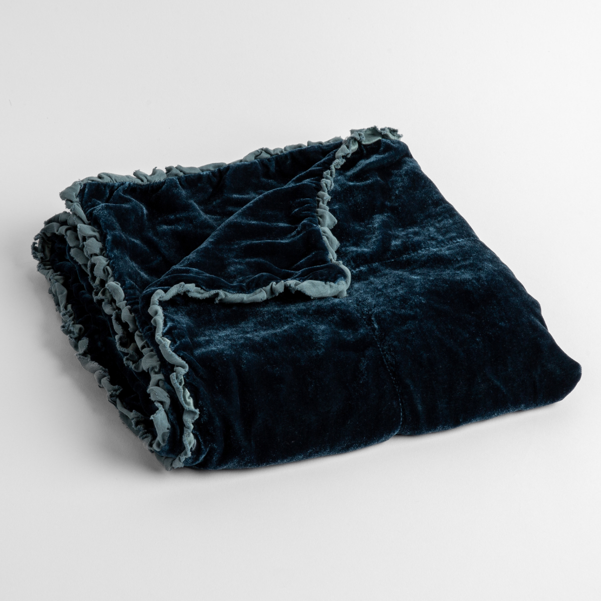 Cenote: silk velvet baby blanket with charmeuse trim shown slightly overhead with a corner folded back to show trim detail against a white background.