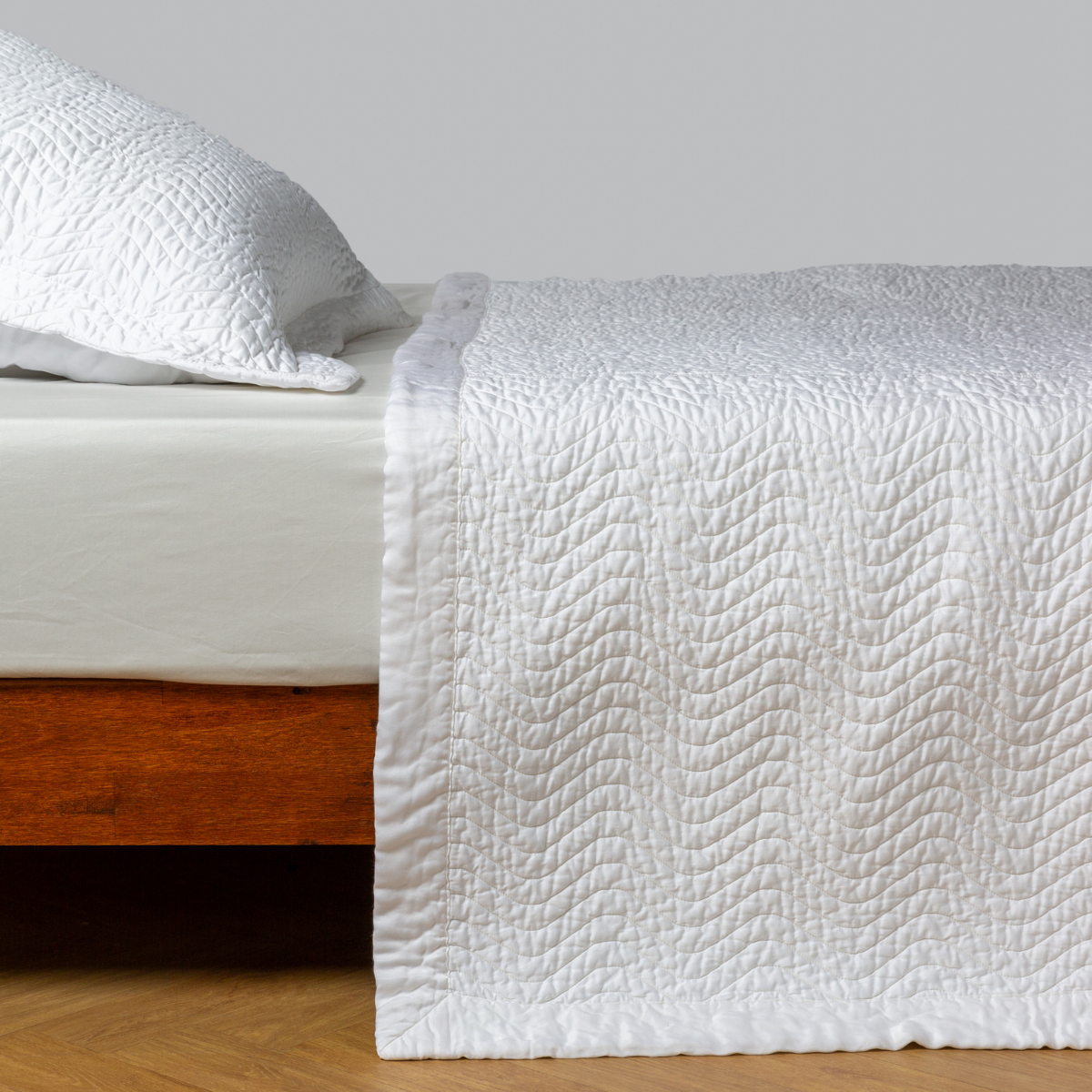 White: quilted cotton sateen coverlet with matching sham on a winter white fitted sheet - side view.