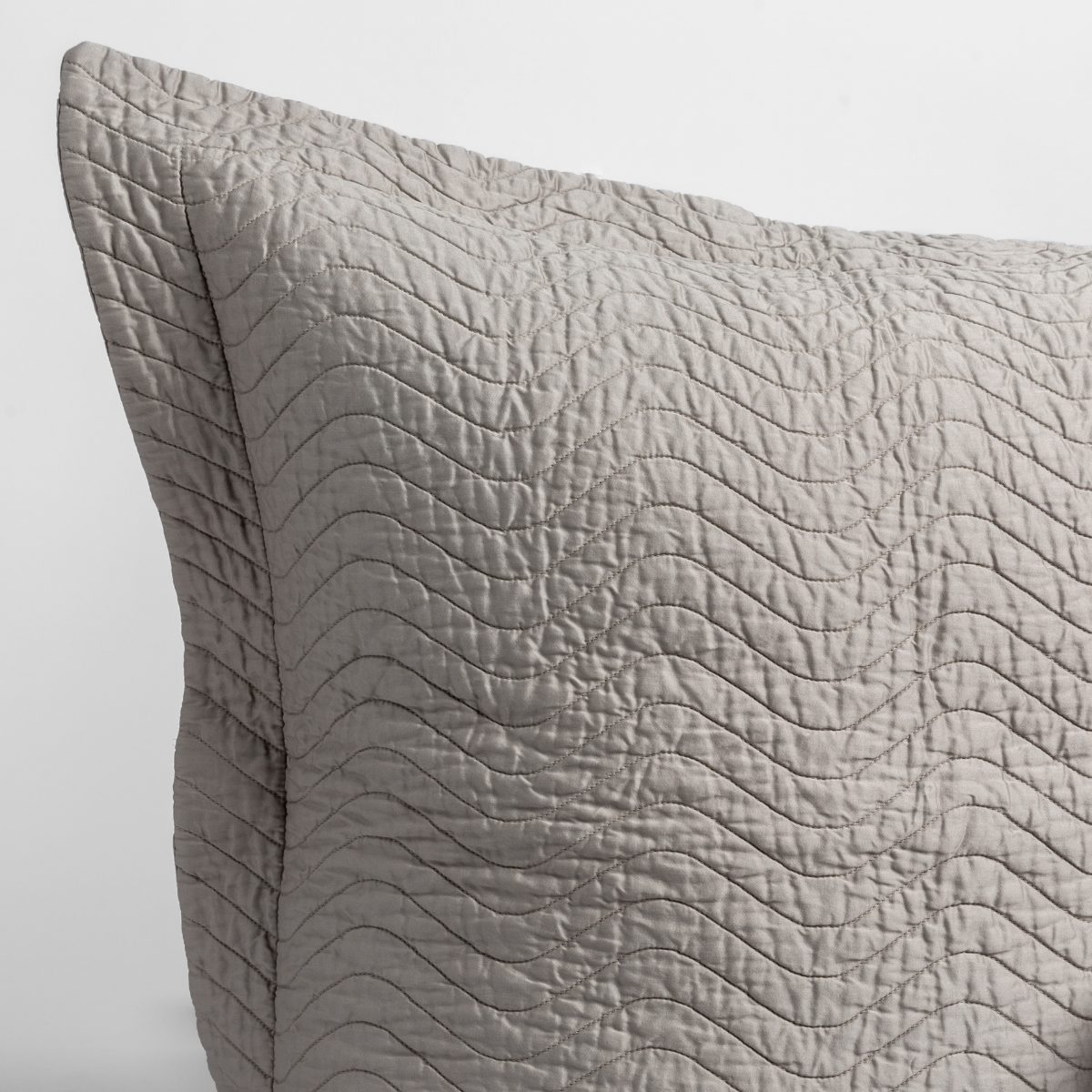 Fog: close up of the corner of a quilted cotton sateen pillow sham - shot against a white background.