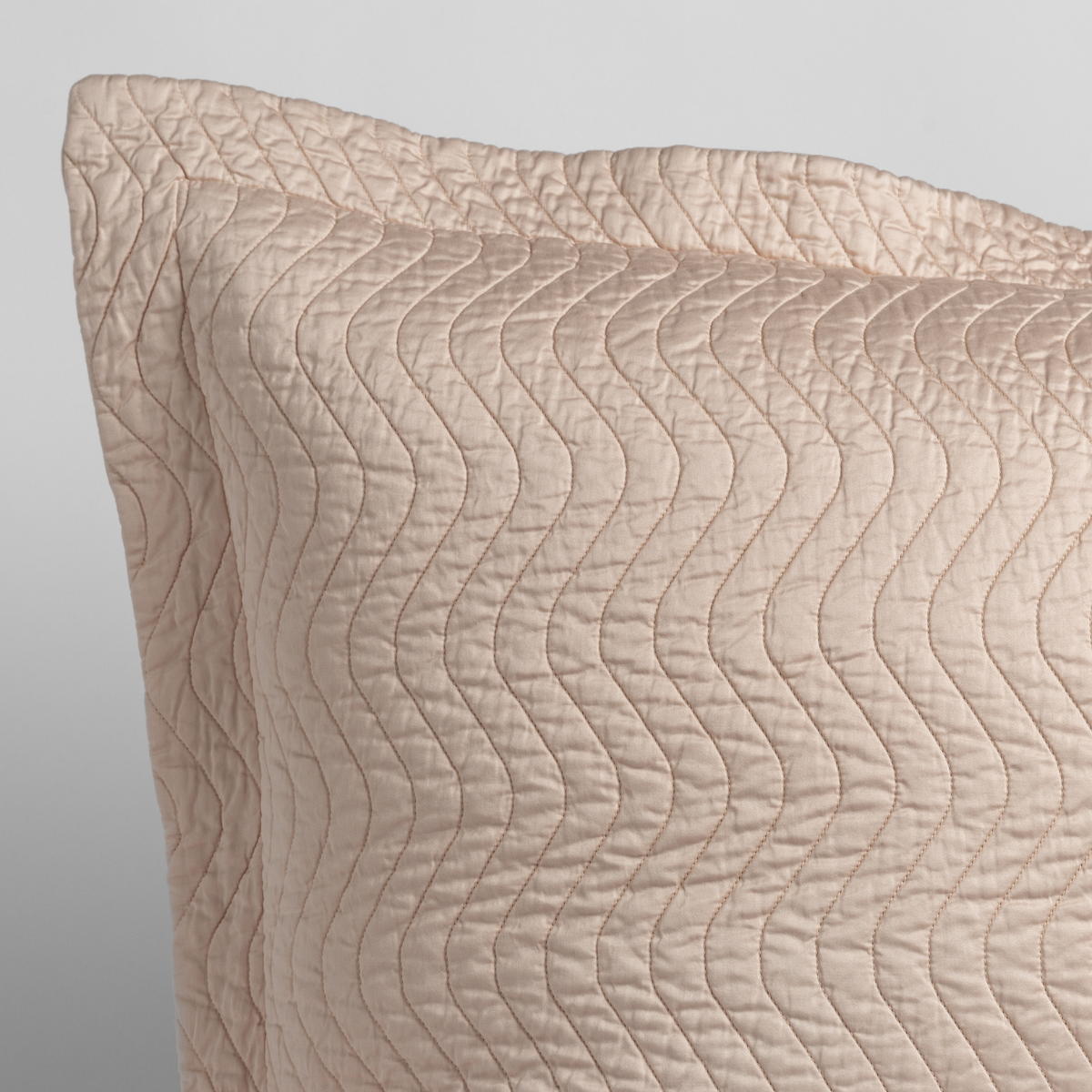 Pearl: close up of the corner of a quilted cotton sateen pillow sham - shot against a white background.
