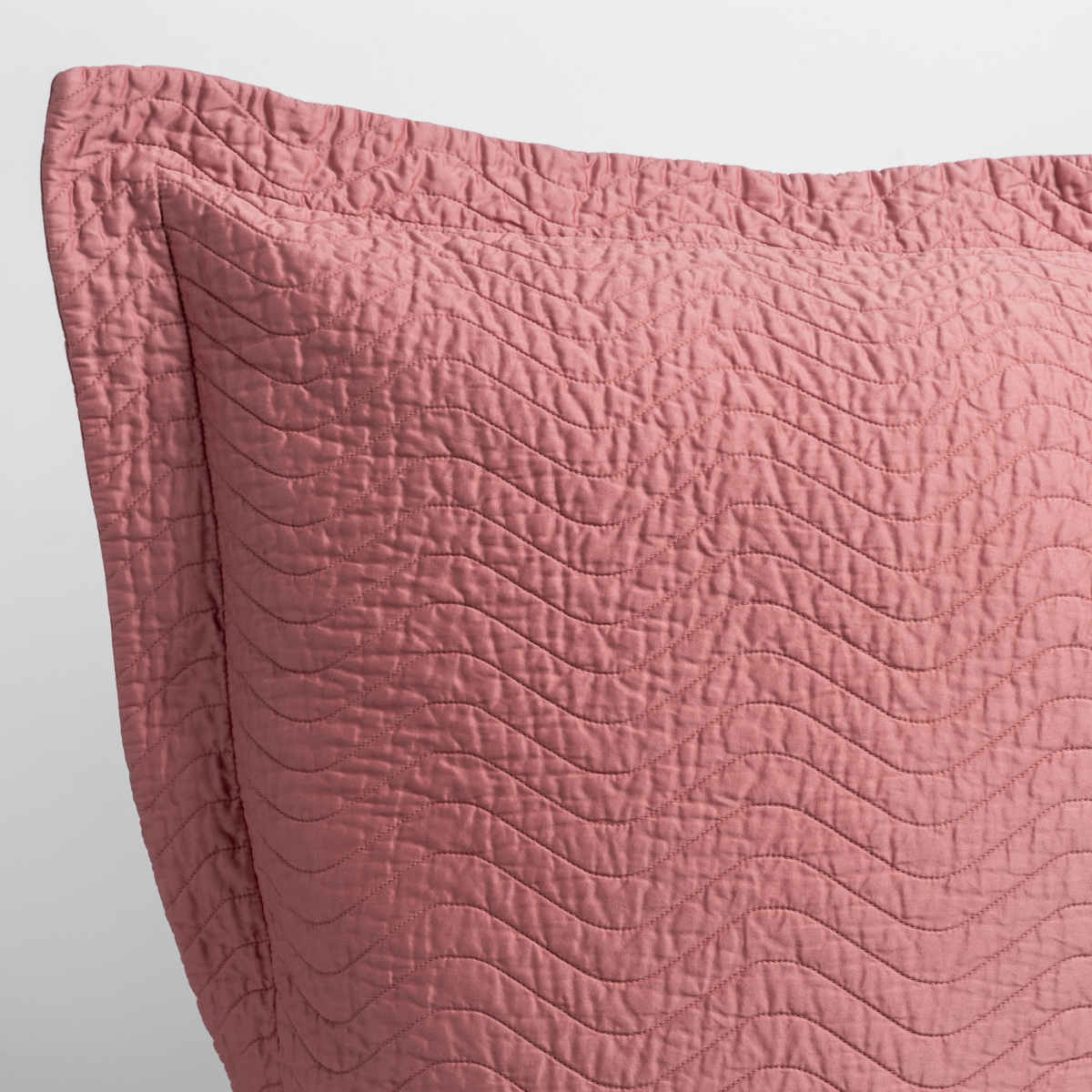 Poppy: close up of the corner of a quilted cotton sateen pillow sham - shot against a white background.