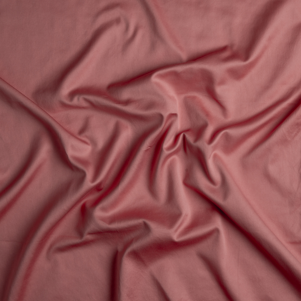 Poppy: A close up of cotton sateen fabric in poppy, a warm coral pink.