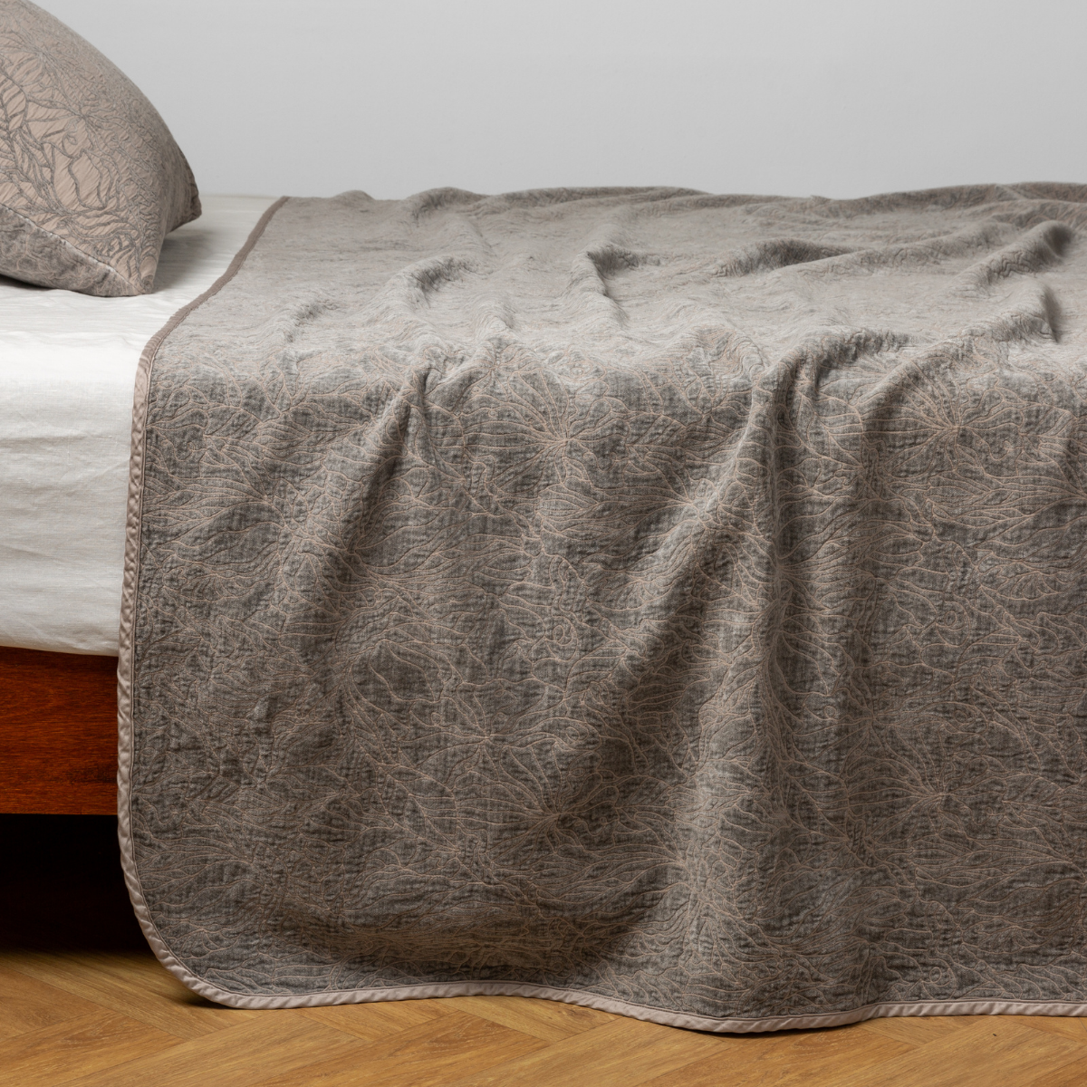 Fog: side view of the chenille jacquard side of a bedspread with the cotton jacquard side showing on the matching sham — shown with a winter white fitted sheet.