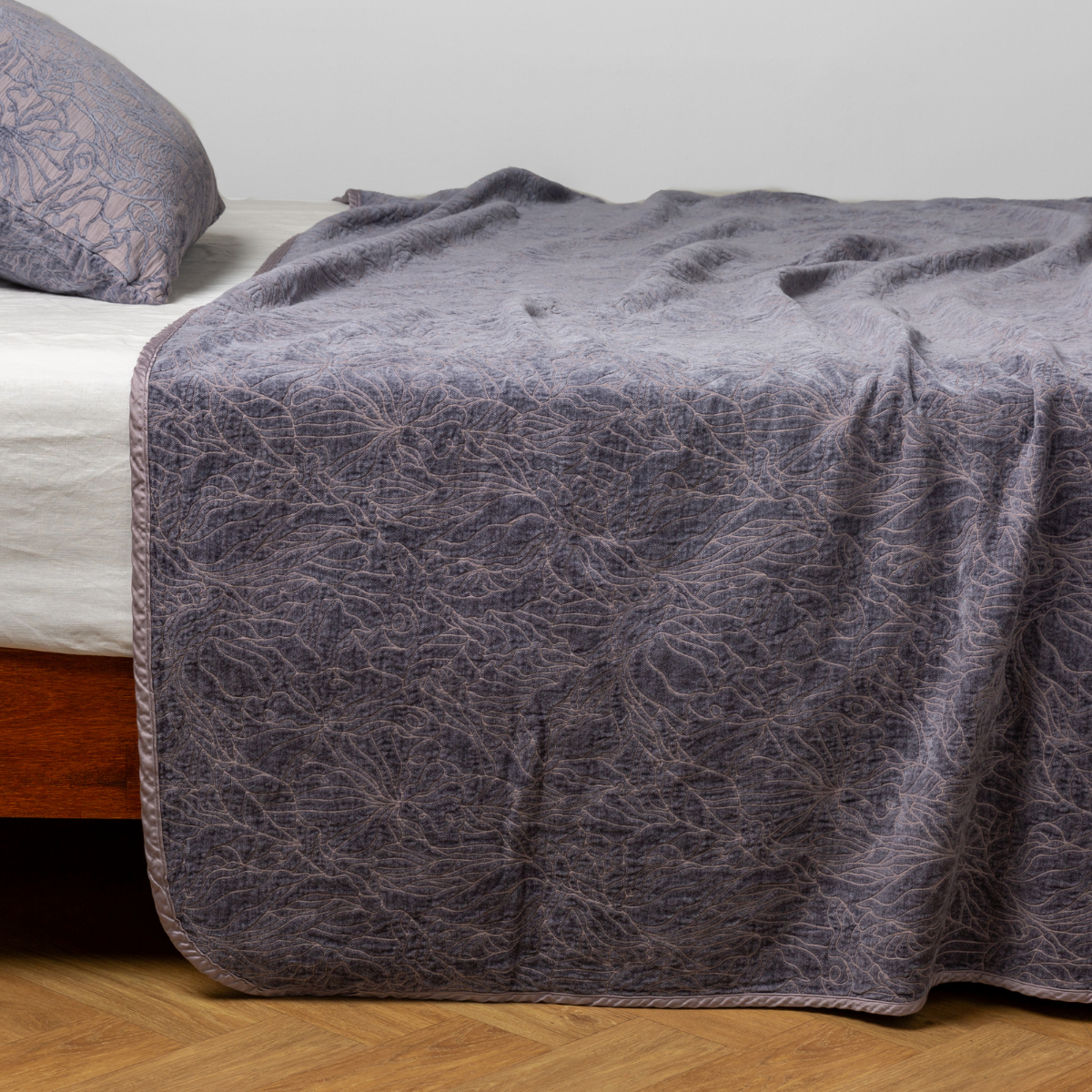 French Lavender: side view of the chenille jacquard side of a bedspread with the cotton jacquard side showing on the matching sham — shown with a winter white fitted sheet.