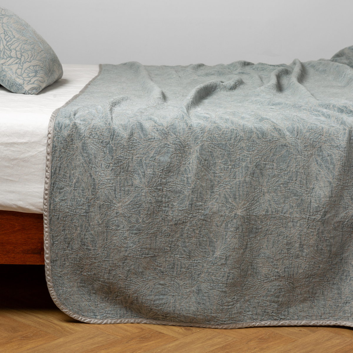 Mineral: side view of the chenille jacquard side of a bedspread with the cotton jacquard side showing on the matching sham — shown with a winter white fitted sheet.
