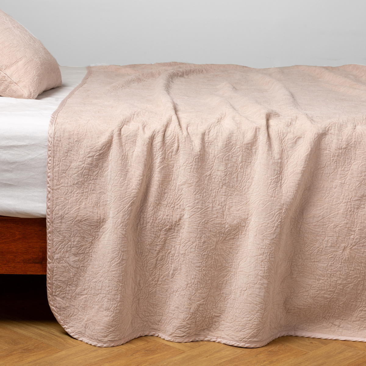 Pearl: side view of the chenille jacquard side of a bedspread with the cotton jacquard side showing on the matching sham — shown with a winter white fitted sheet.