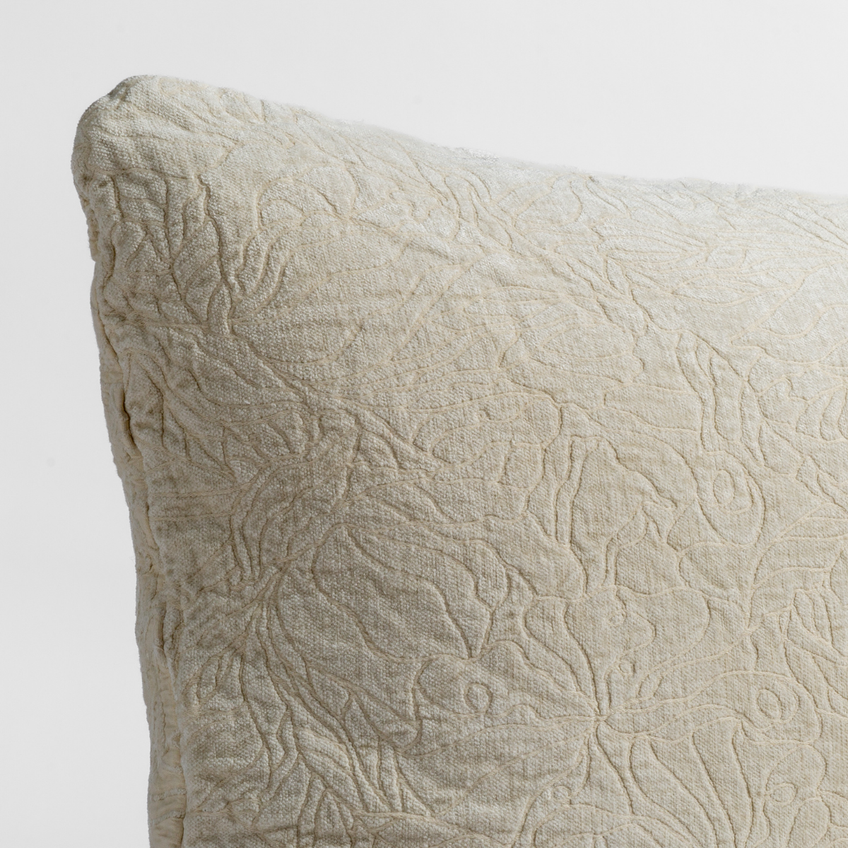 Parchment: close up of the chenille jacquard corner of a pillow cushion with a single-line floral pattern.