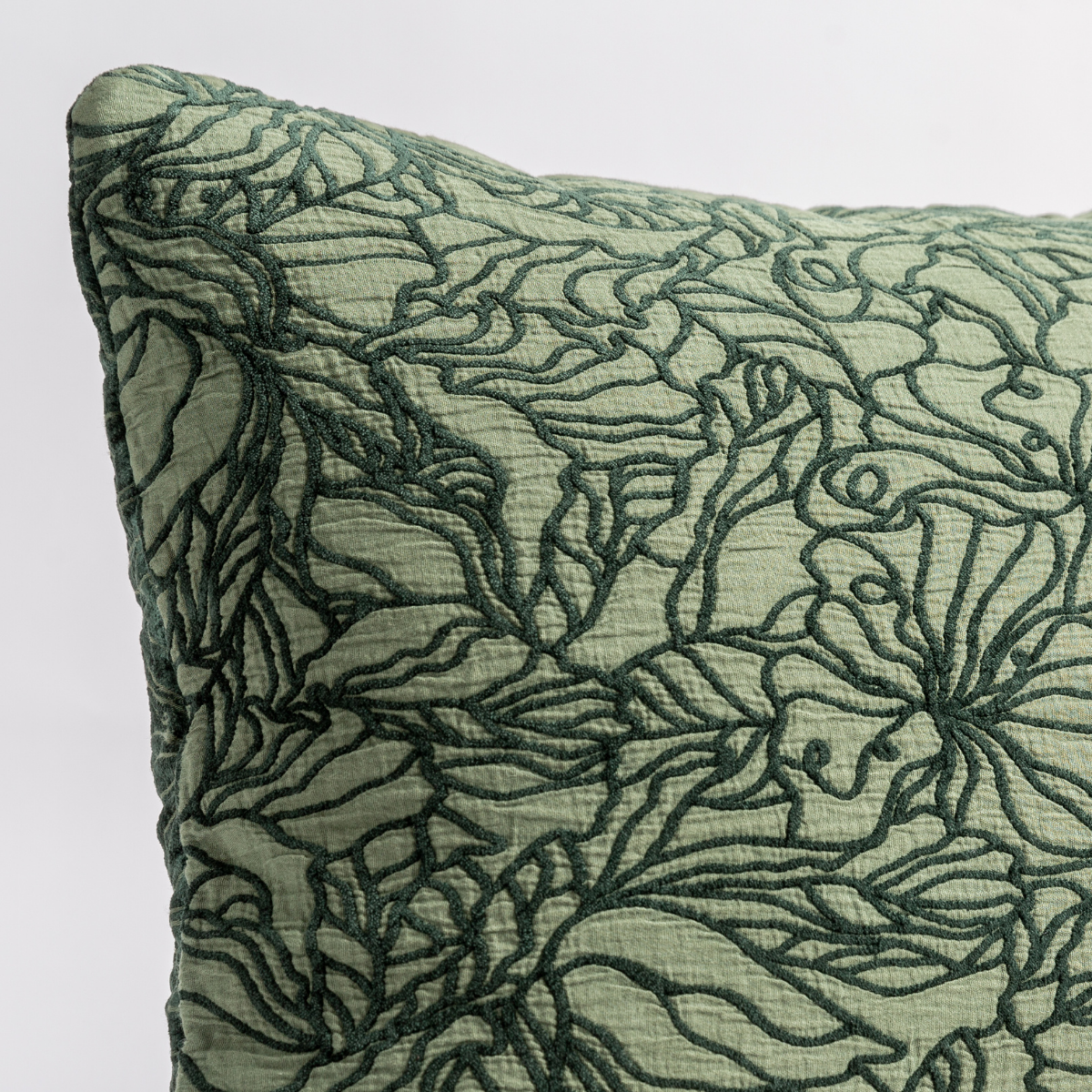 Juniper: close up of the cotton jacquard corner of a pillow cushion with a single-line floral pattern.