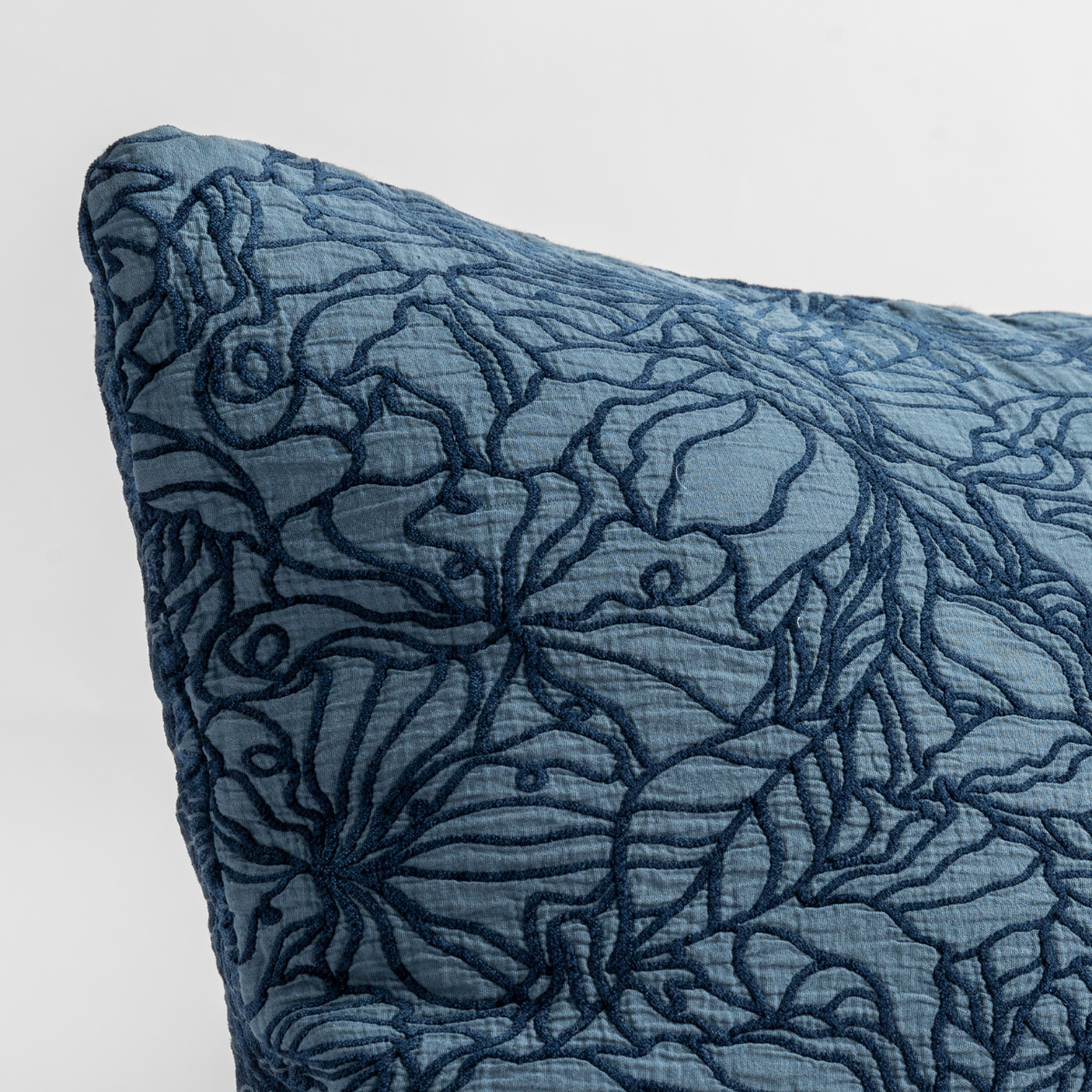 Midnight: close up of the cotton jacquard corner of a pillow cushion with a single-line floral pattern.