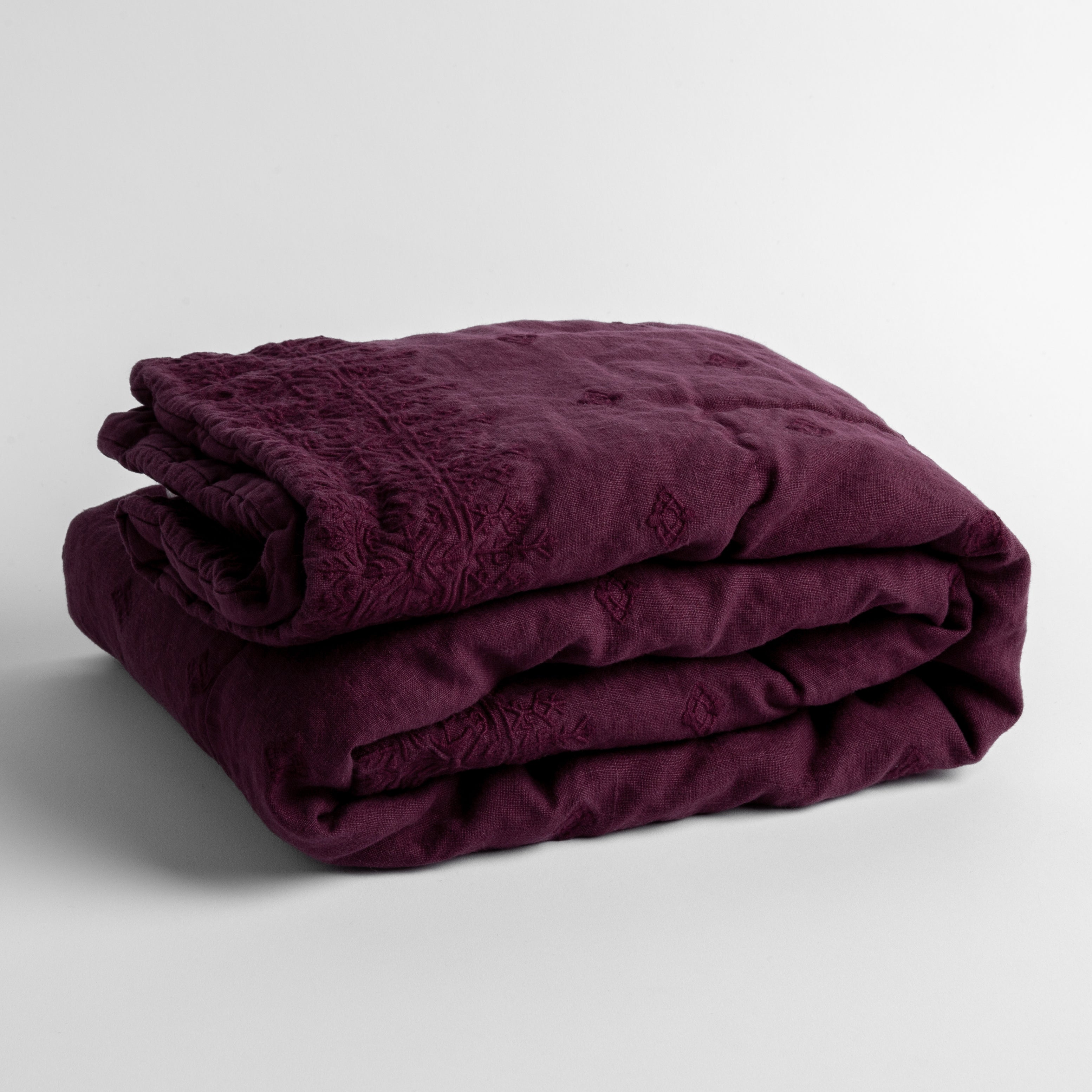 Fig: embroidered linen baby blanket folded and shown overhead from a slight angle against a white background.