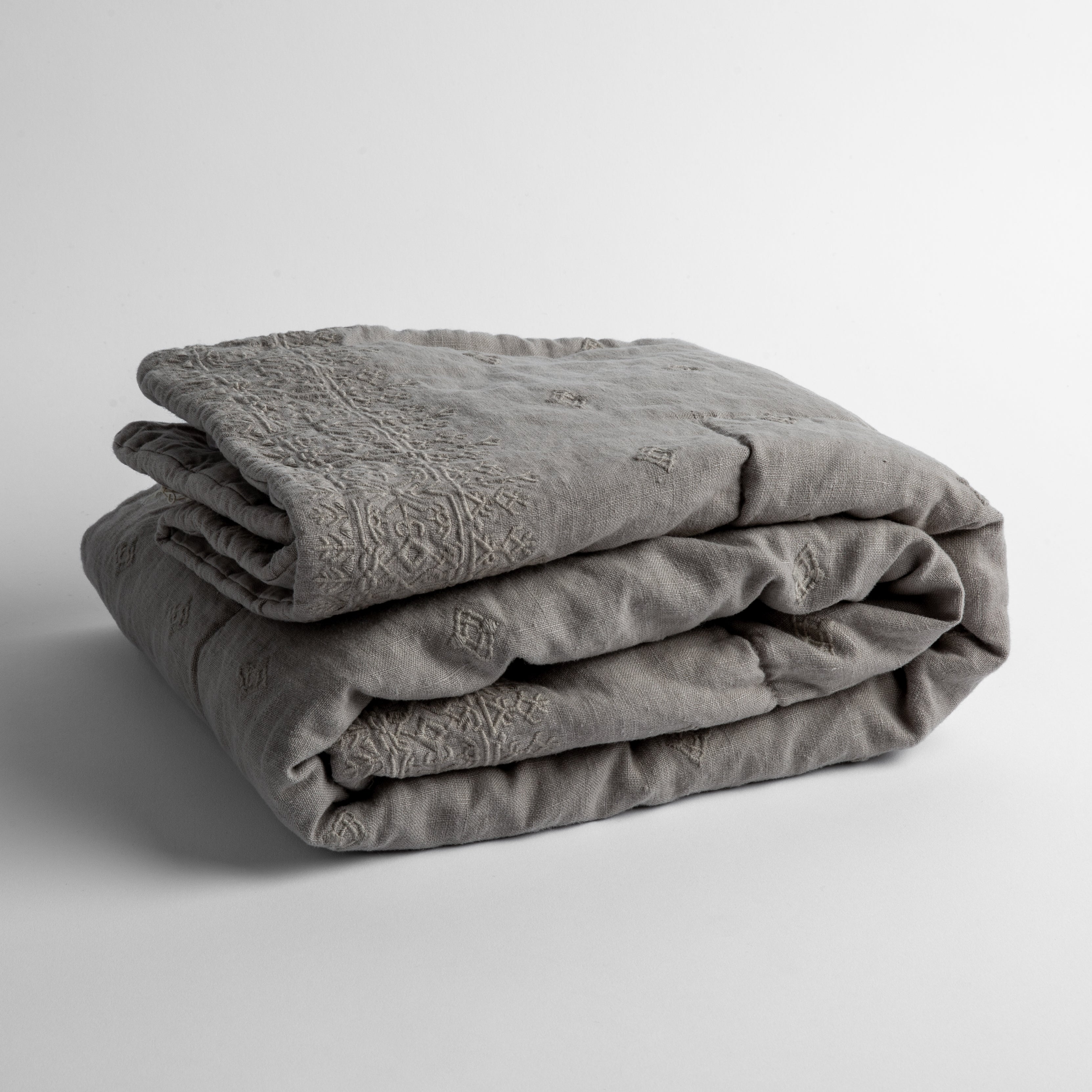 Fog: embroidered linen baby blanket folded and shown overhead from a slight angle against a white background.
