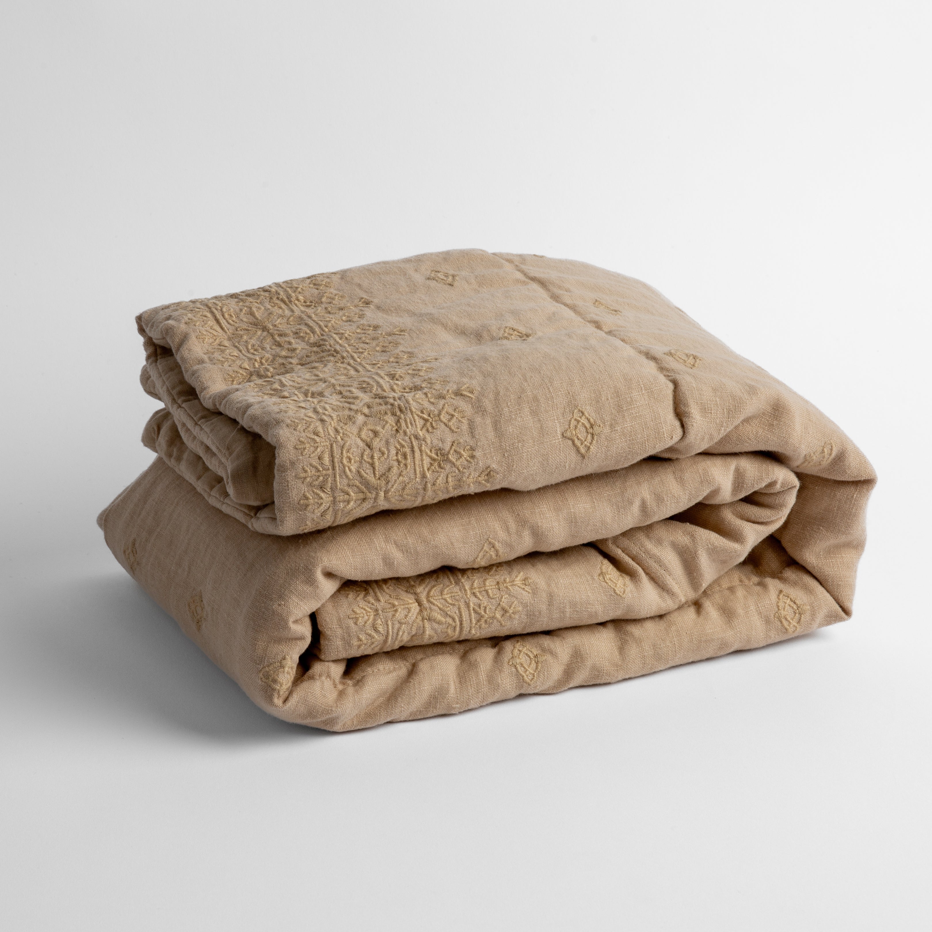 Honeycomb: embroidered linen baby blanket folded and shown overhead from a slight angle against a white background.