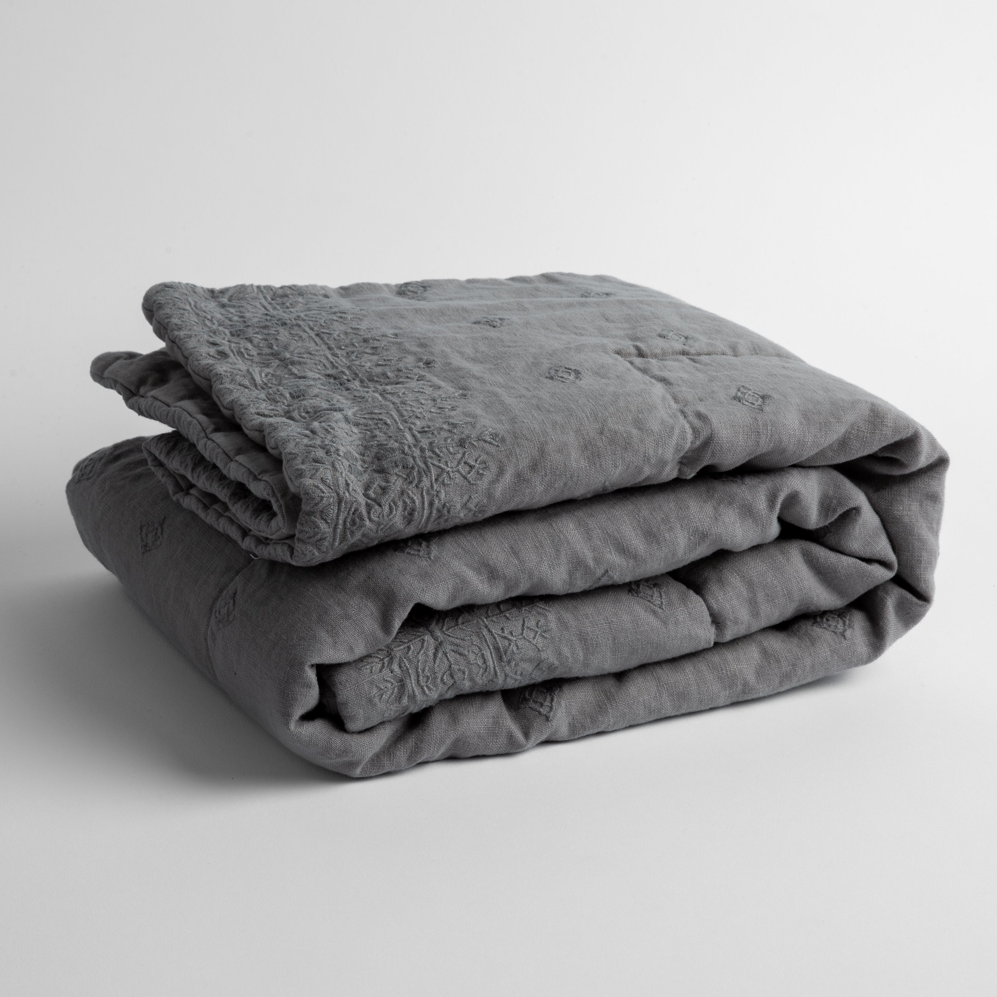 Moonlight: embroidered linen baby blanket folded and shown overhead from a slight angle against a white background.