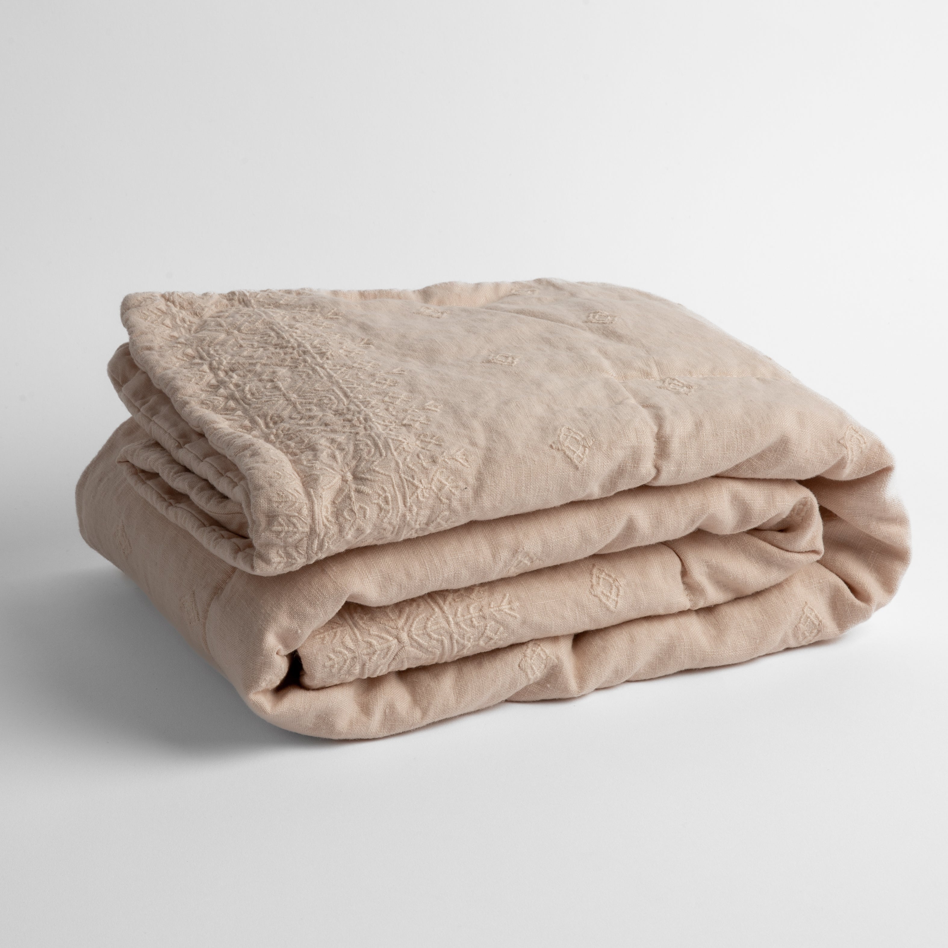 Pearl: embroidered linen baby blanket folded and shown overhead from a slight angle against a white background.
