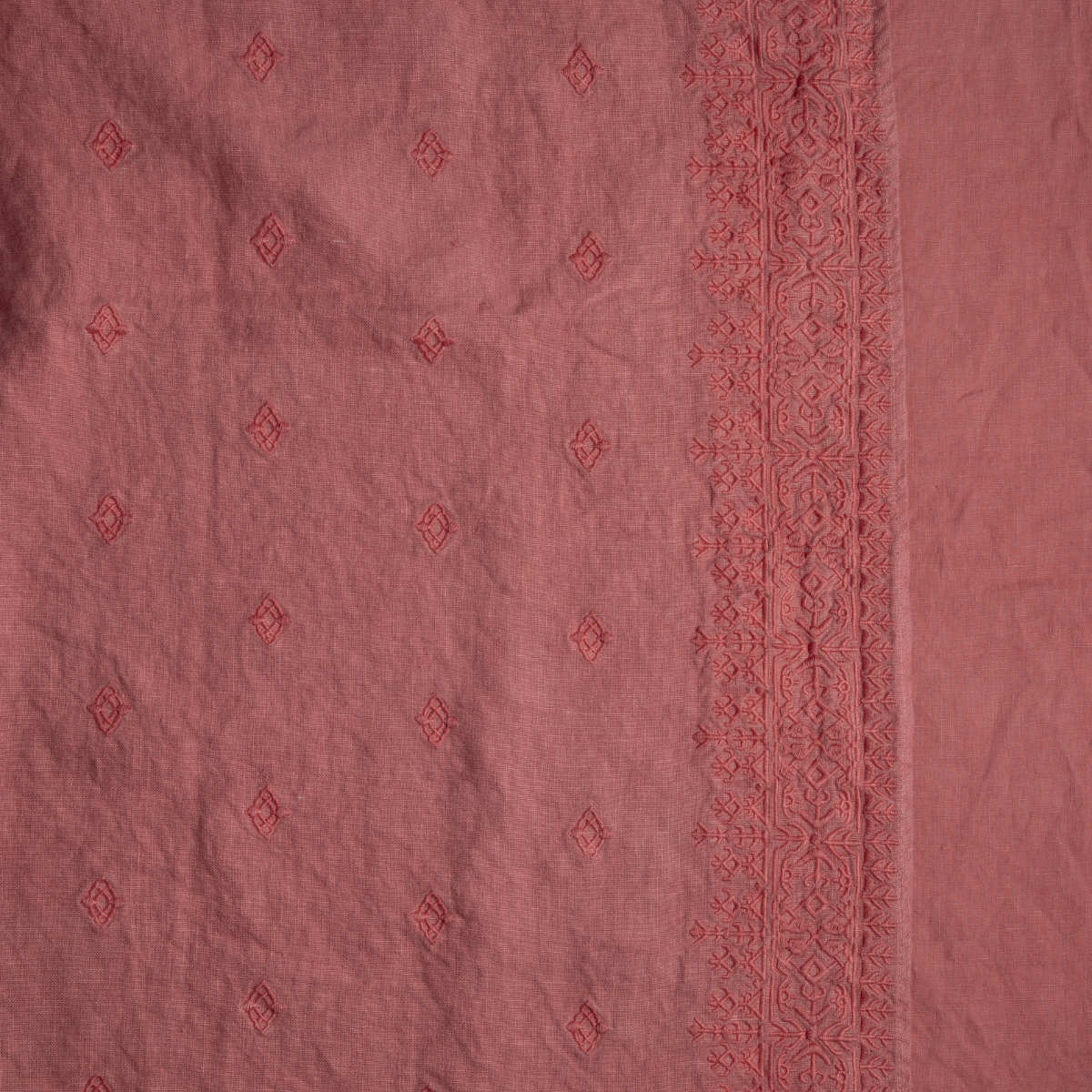 Poppy: A close up of embroidered midweight linen fabric in poppy, a warm coral pink.