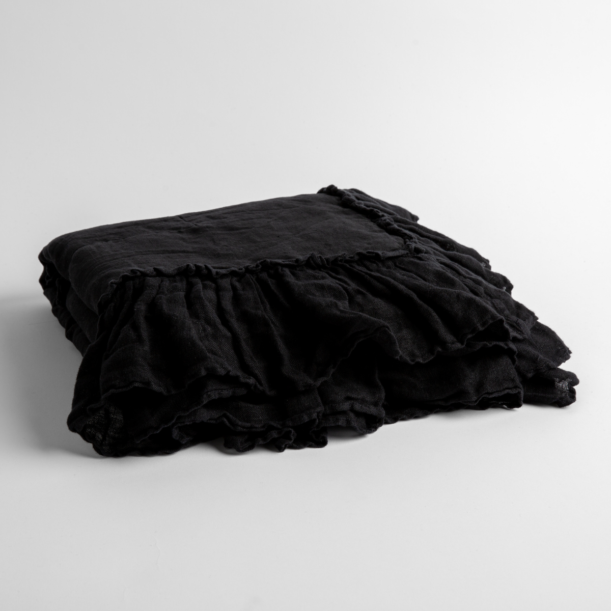 Corvino: a folded linen with linen whisper ruffled blanket folded and positioned to show the ruffle detail against a white background and slightly overhead.