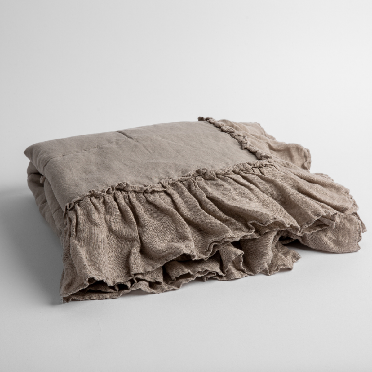 Fog: a folded linen with linen whisper ruffled blanket folded and positioned to show the ruffle detail against a white background and slightly overhead.