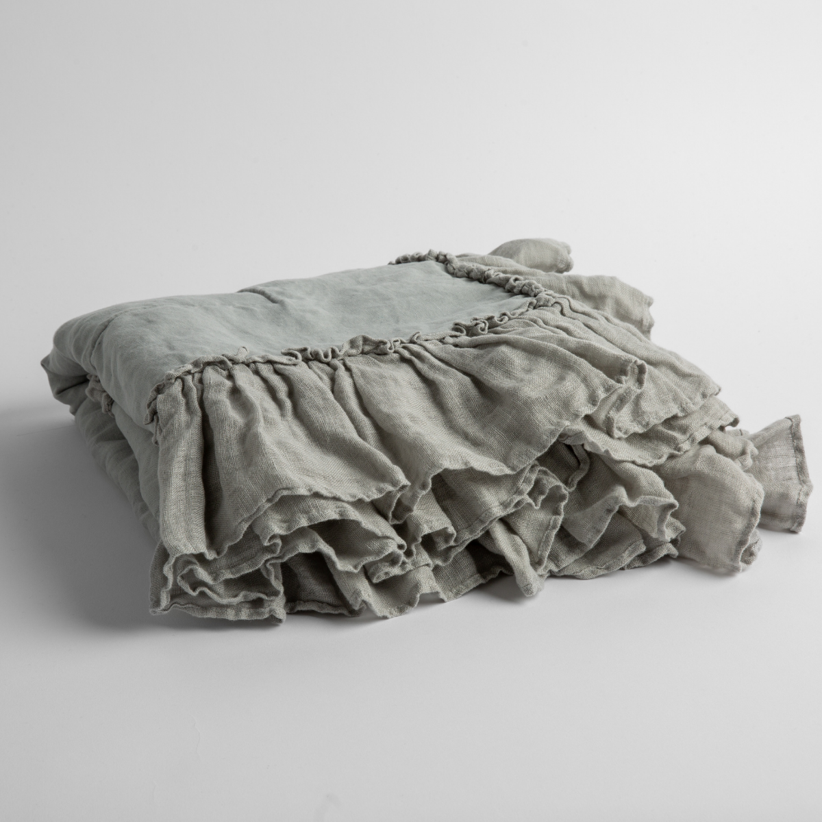 Mineral: a folded linen with linen whisper ruffled blanket folded and positioned to show the ruffle detail against a white background and slightly overhead.