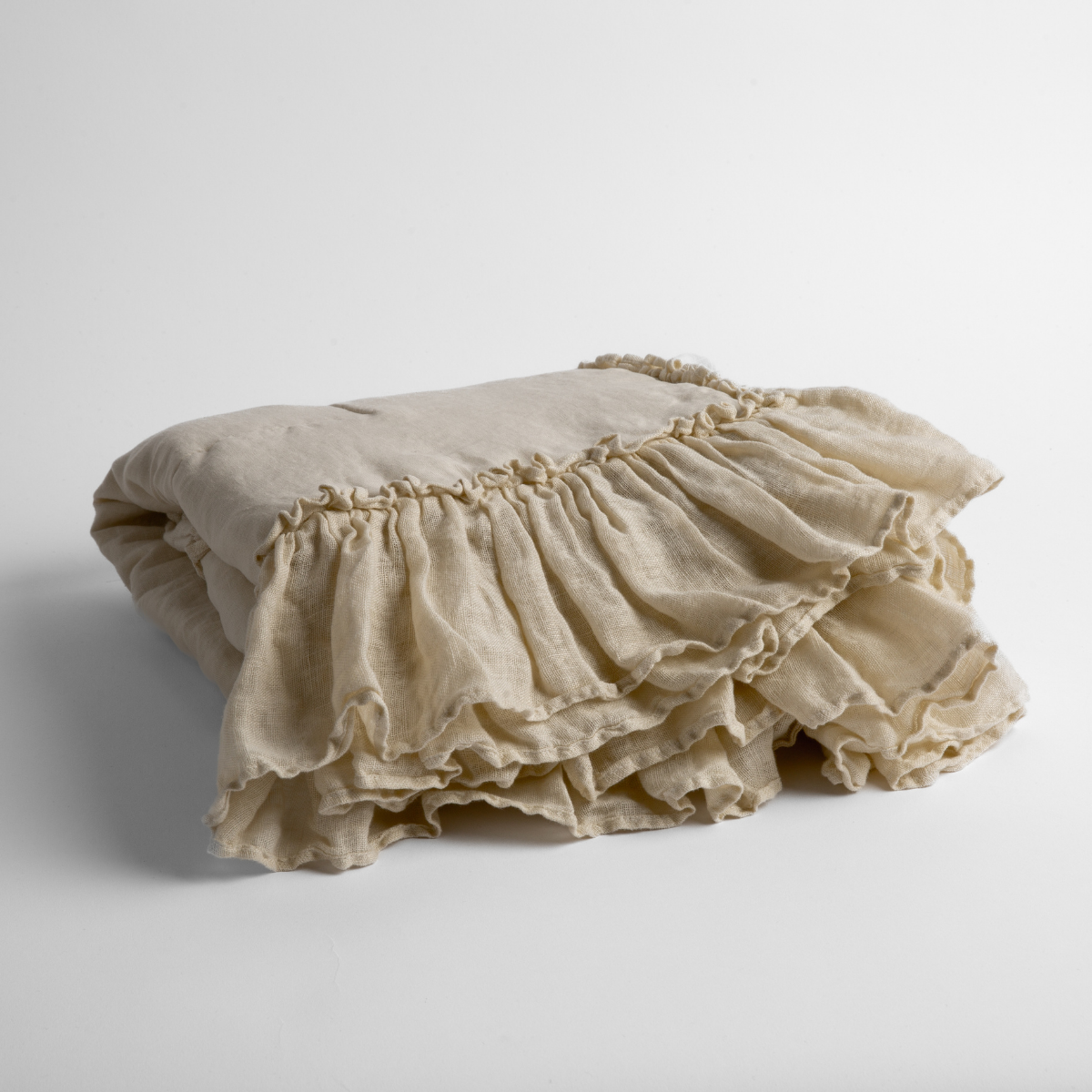 Parchment: a folded linen with linen whisper ruffled blanket folded and positioned to show the ruffle detail against a white background and slightly overhead.