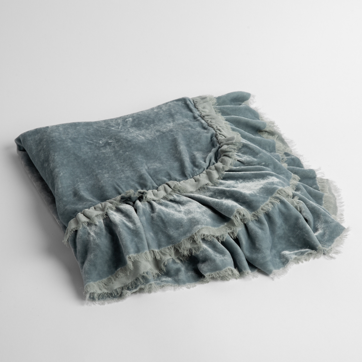 Cloud: an overhead shot of a folded silk velvet baby blanket with a raw-edged eyelash ruffle detail.