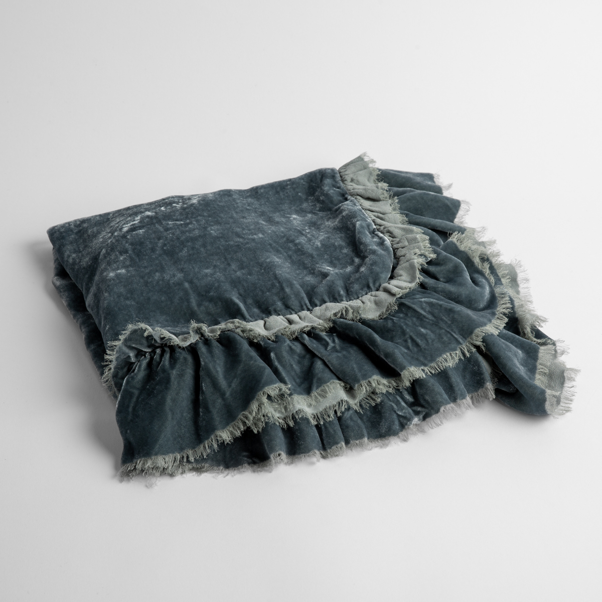 Mineral: an overhead shot of a folded silk velvet baby blanket with a raw-edged eyelash ruffle detail.