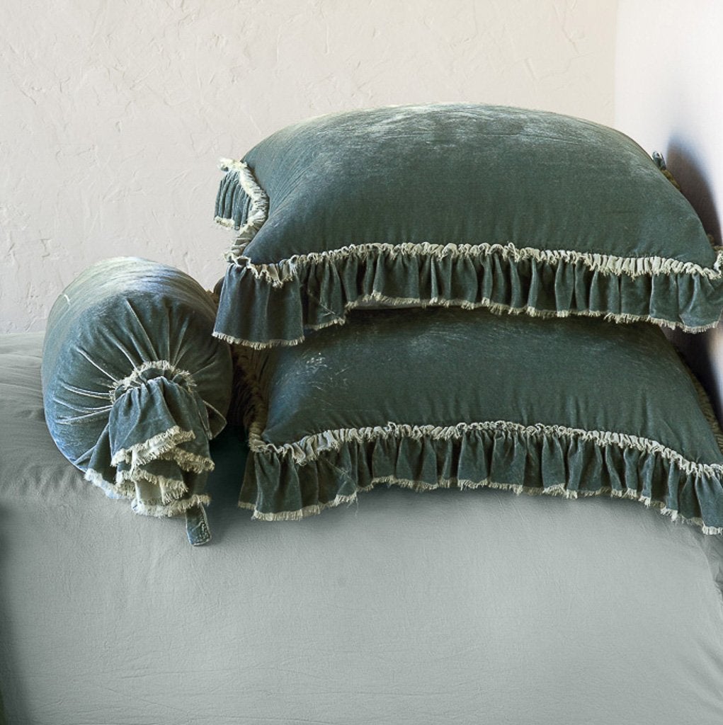 : Two Loulah shams laying flat, stacked on a bed with matching bolster and on-tone sheets - eucalyptus. Close-up side view highlights the ruffle trim.