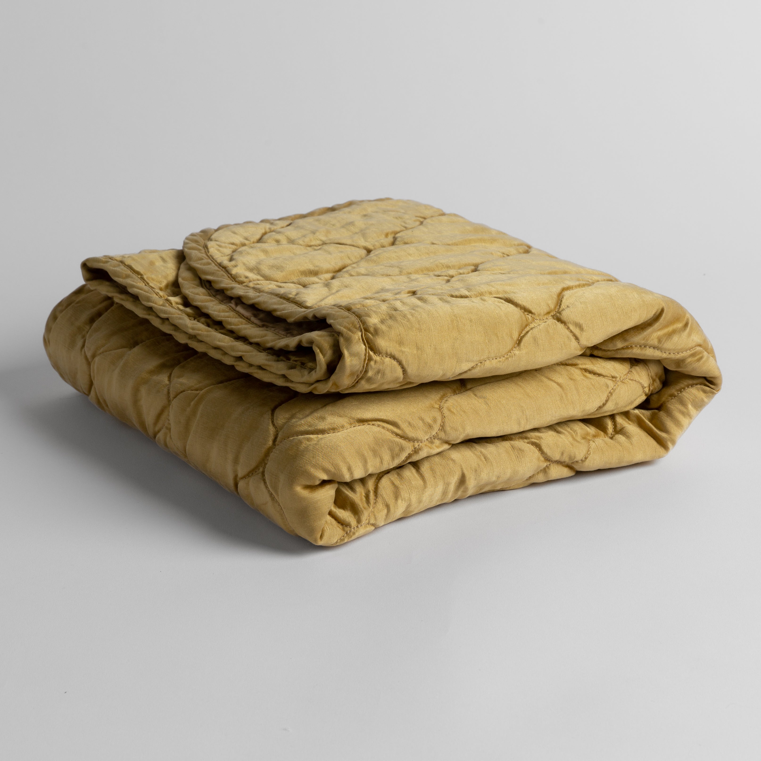 Honeycomb: quilted charmeuse blanket folded and shown against a white background from a slight overhead angle.