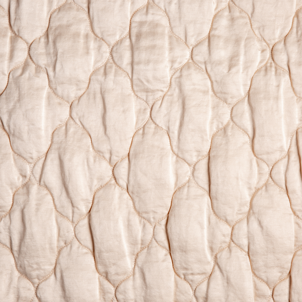 Pearl: A close up of quilted charmeuse fabric in pearl, a nude-like, soft rose pink tone.