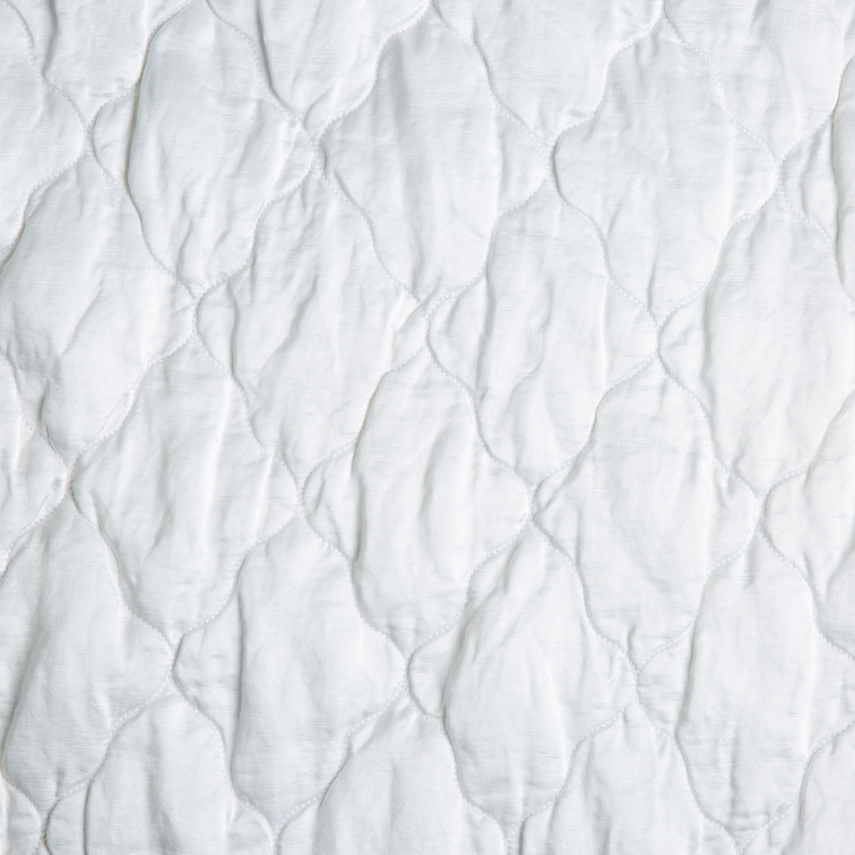 White: A close up of quilted charmeuse fabric in classic white.