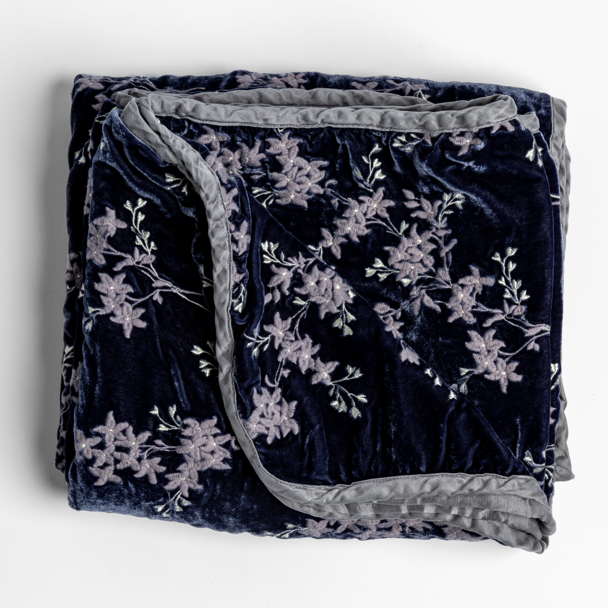 Folded embroidered silk velvet blanket with charmeuse trim shot from overhead to show floral pattern